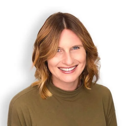 A smiling woman with shoulder-length, wavy, light brown hair wearing an olive green top.