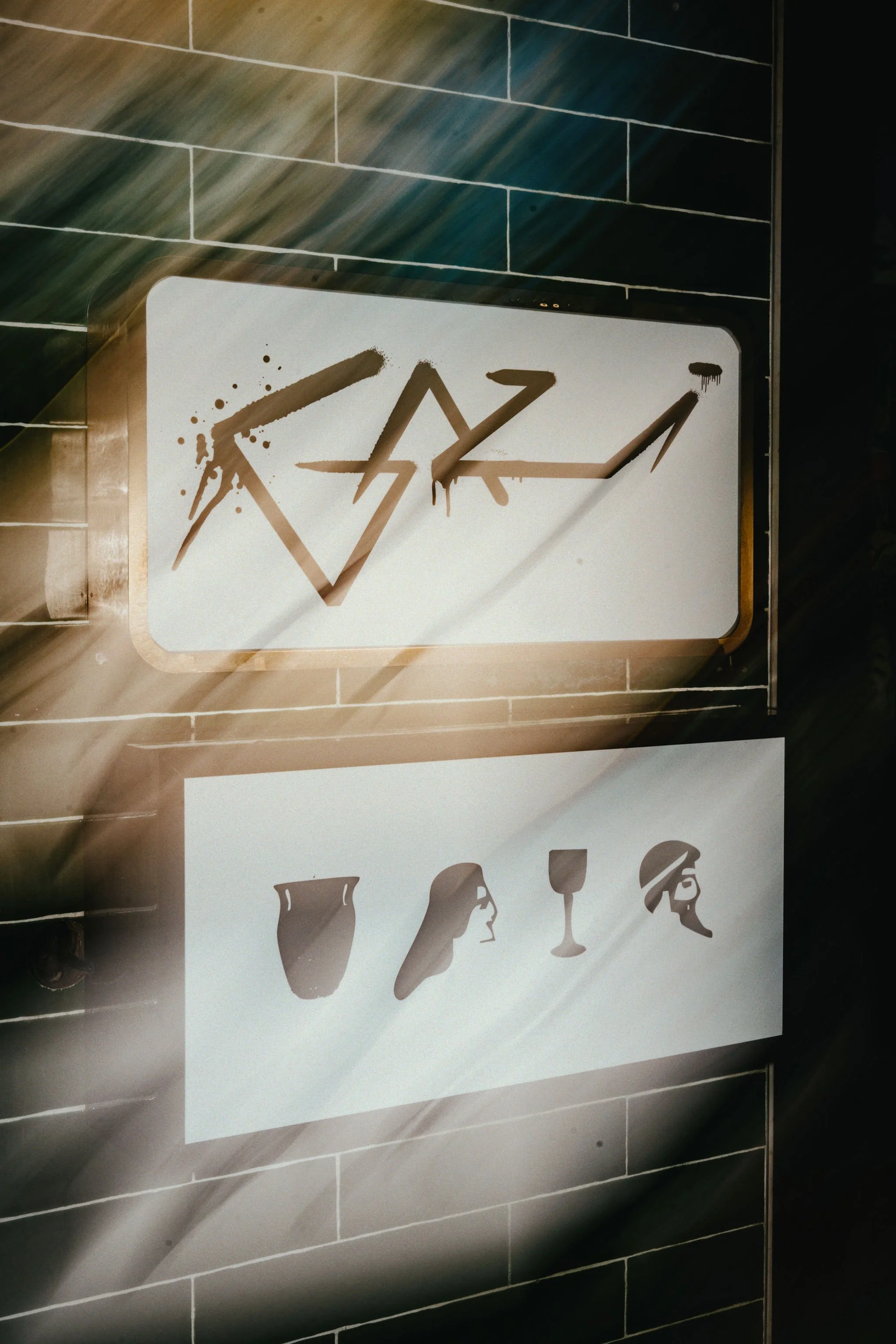 Graffiti-style artwork on two signs featuring abstract faces made with different pottery shapes and graffiti-style text