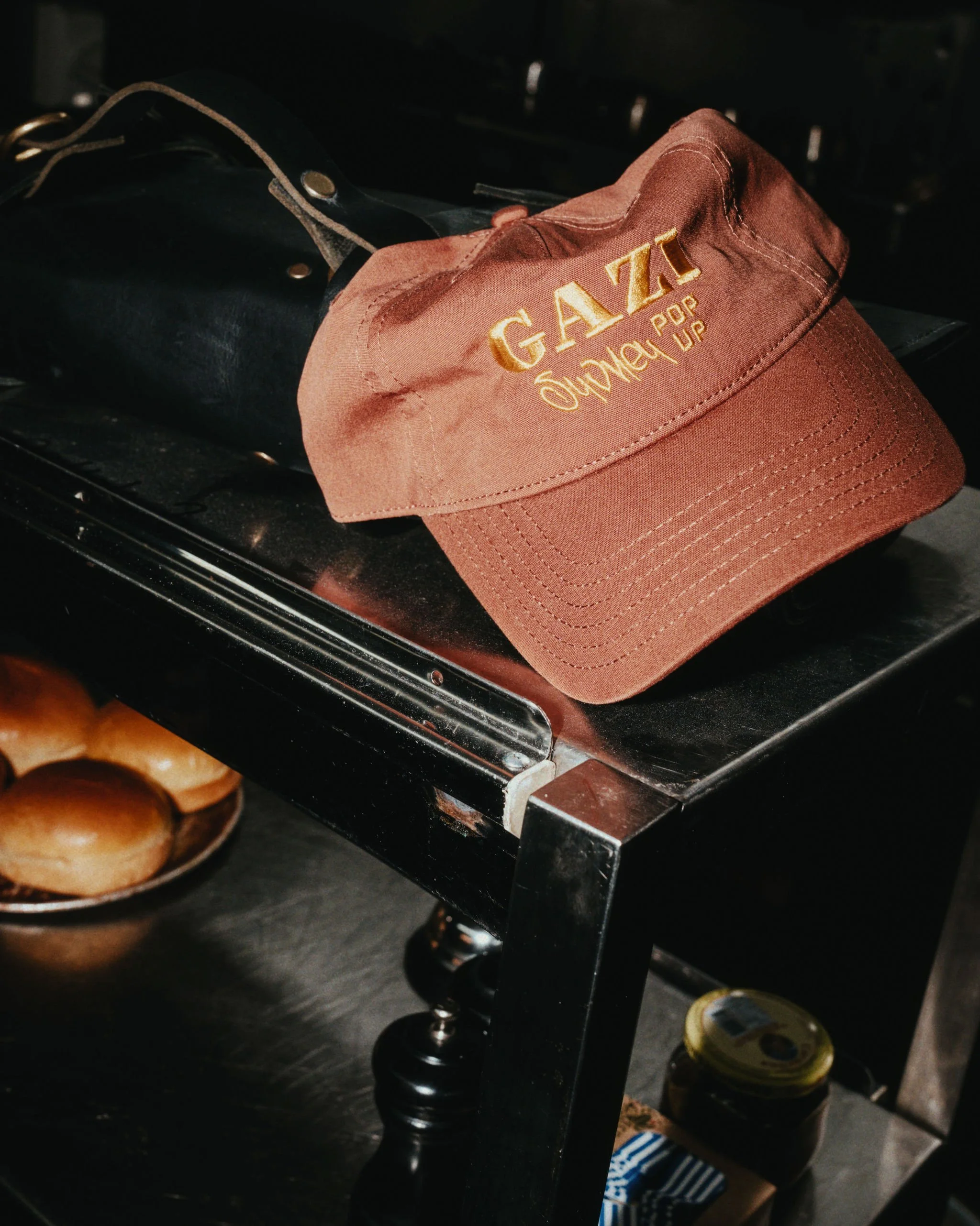 A brown GAZZ Power Outdoor cap resting on a black metal table in a kitchen setting.