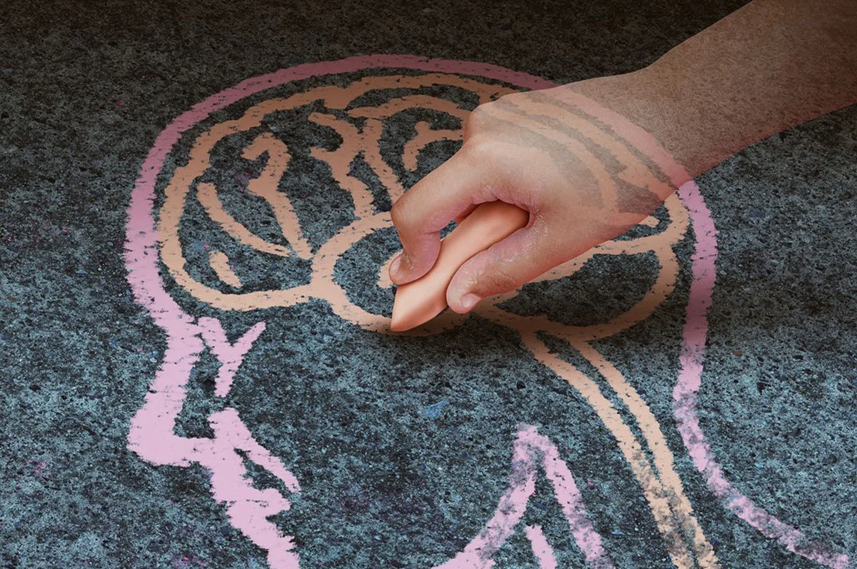 Ett hand som ritar ett ansikte på ett trottoar med rosa krita.