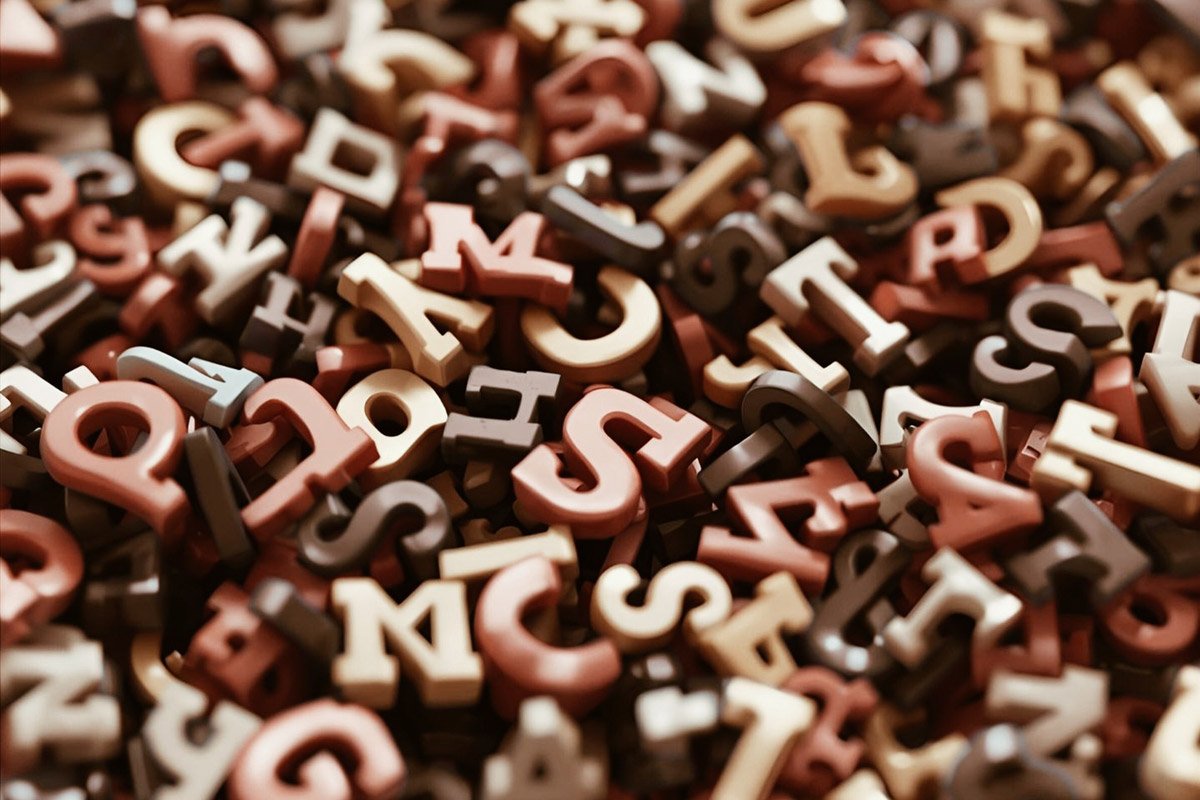 Färgglada små bokstavsfigurer i rika färger, spridda över ett feld t.