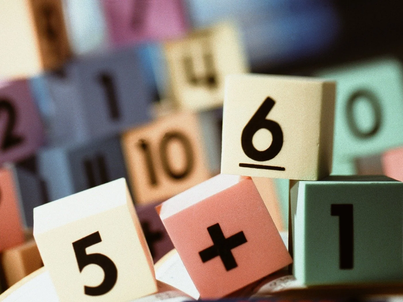 Färgade nummerblock med siffror och ett plus-tecken, där det tydligaste blocket visar siffran 6.