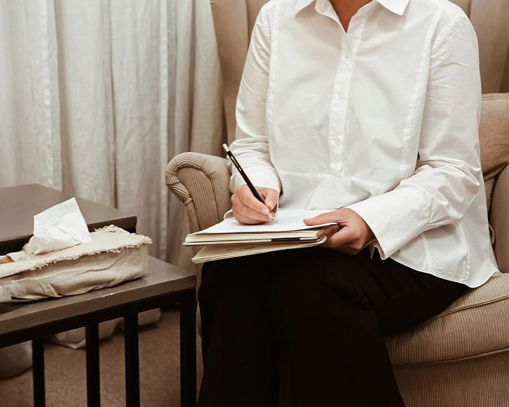 Person som använder en surfplatta med stylus, samt en dator i bakgrunden på ett skrivbord.