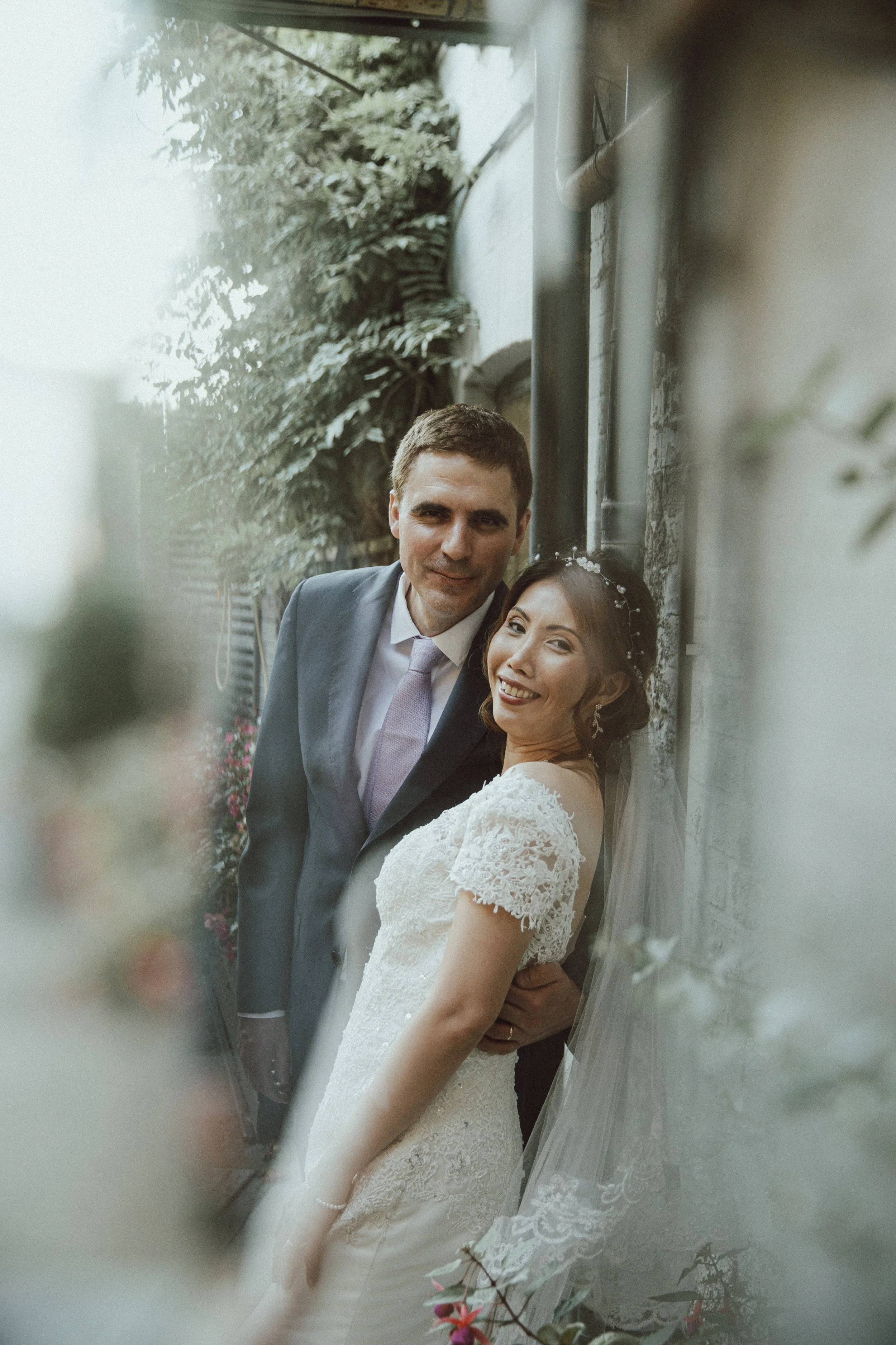 Grace and Nicholas together beside an ivy-covered wall during their wedding in Boston, Lincolnshire.