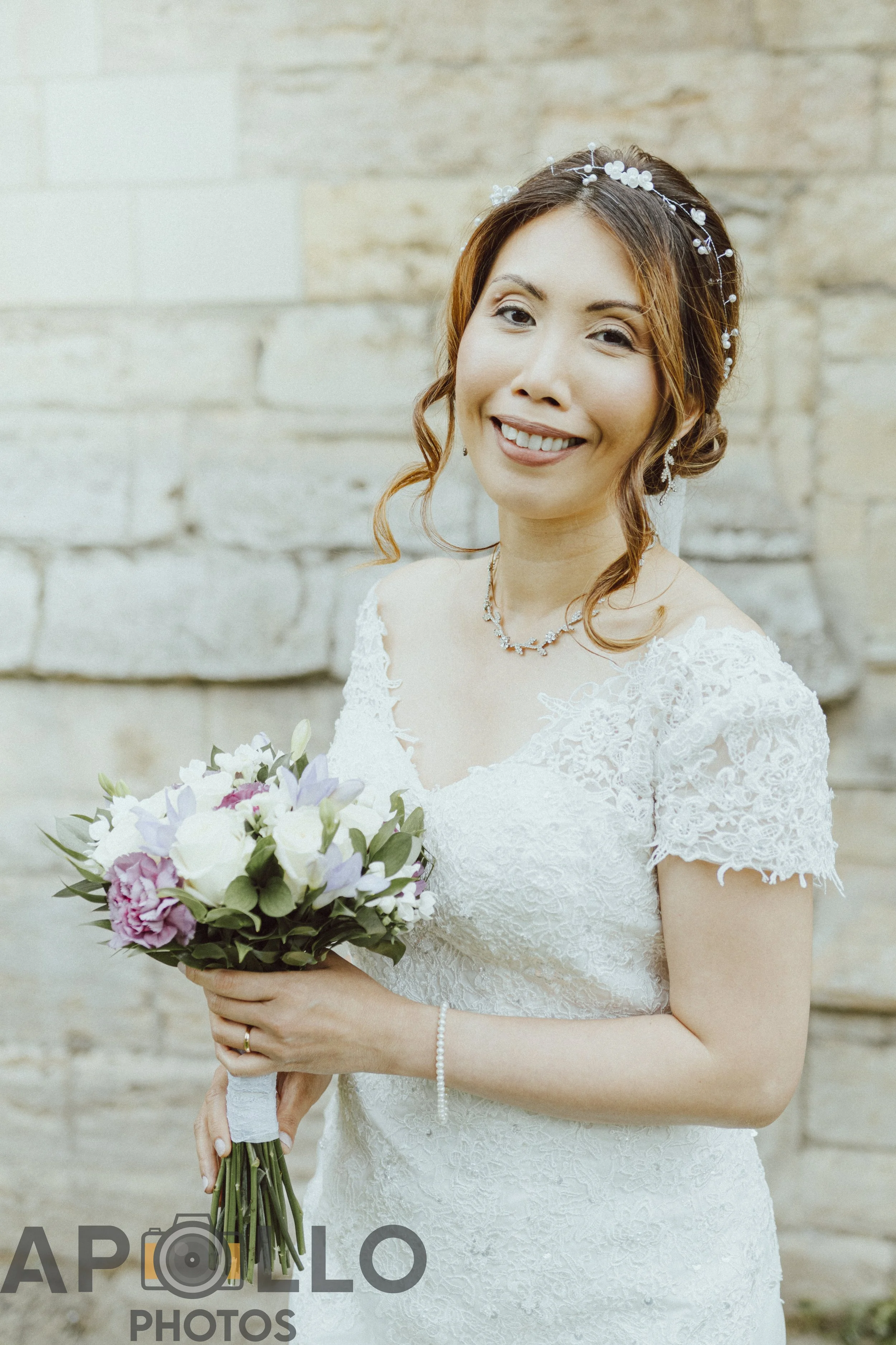 Grace smiling with her bouquet beside the stonework of St Botolph’s Church, Boston Stump, on her wedding day in Boston.