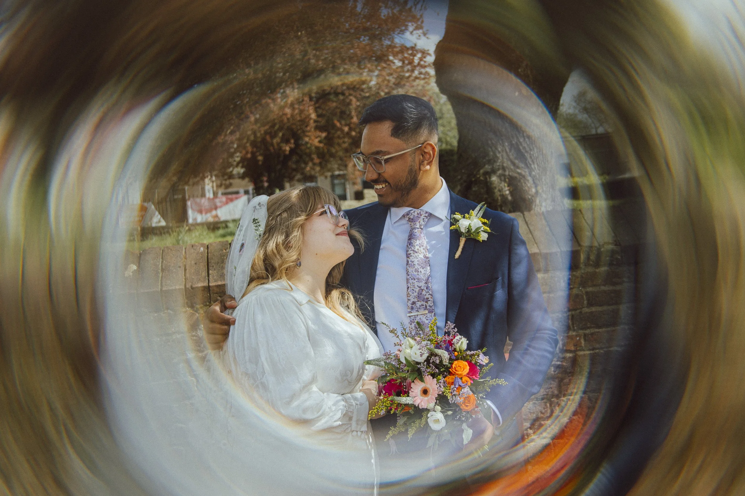 A couple looking at each other outside Ilkeston Registration Office, framed by a circular glass effect.