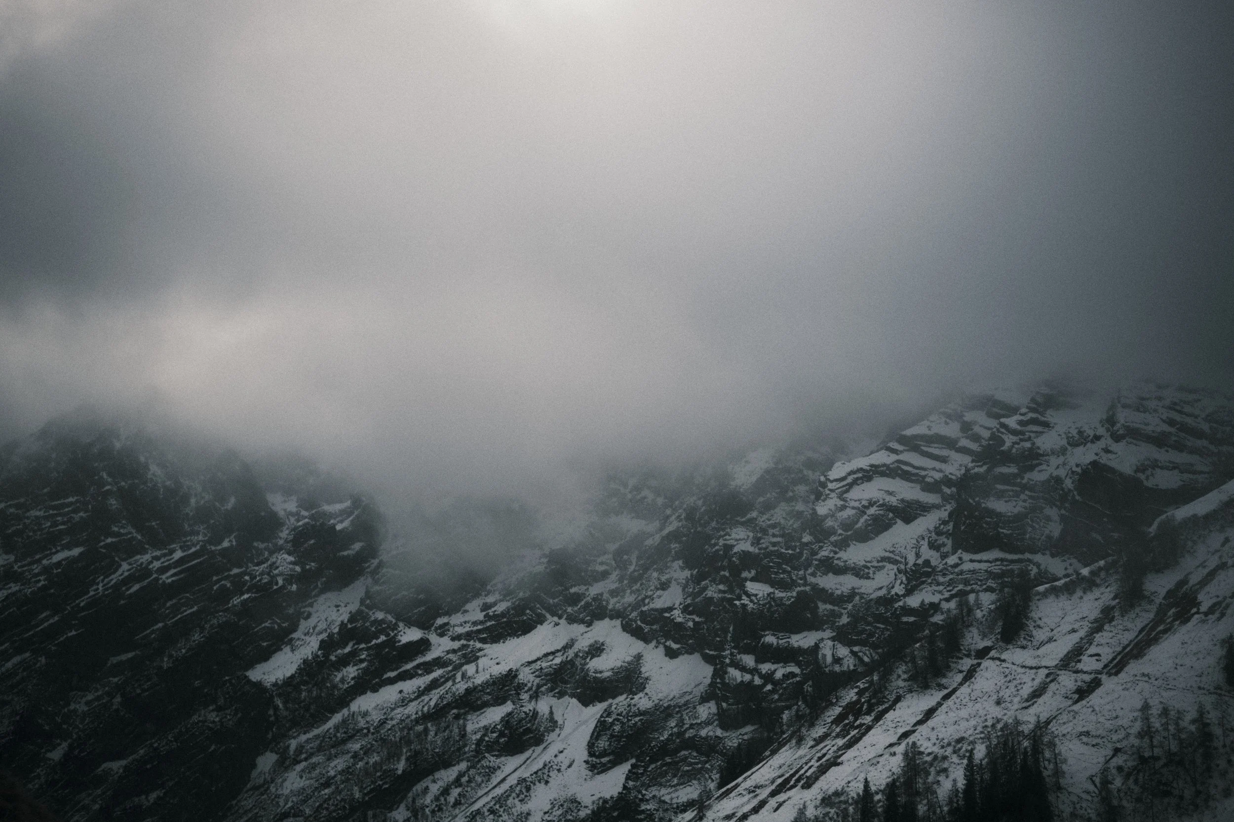 Berge mit Schneedecke, teilweise von Wolken bedeckt, in einer nebligen Berglandschaft. Erik Schereder