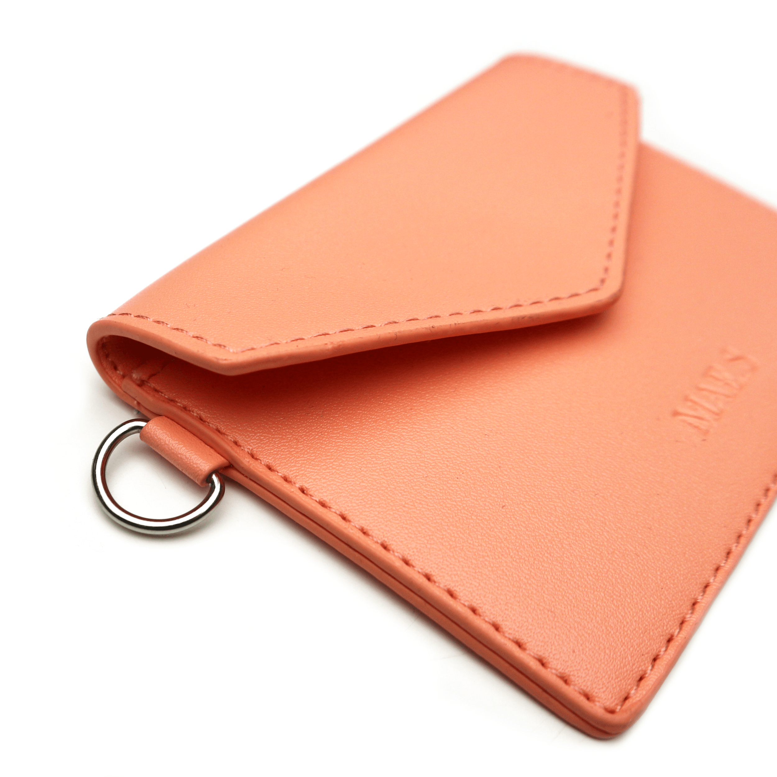 Close-up of a peach-colored leather wallet with a metal ring on one corner, and the word 'WALK' embossed on the surface.