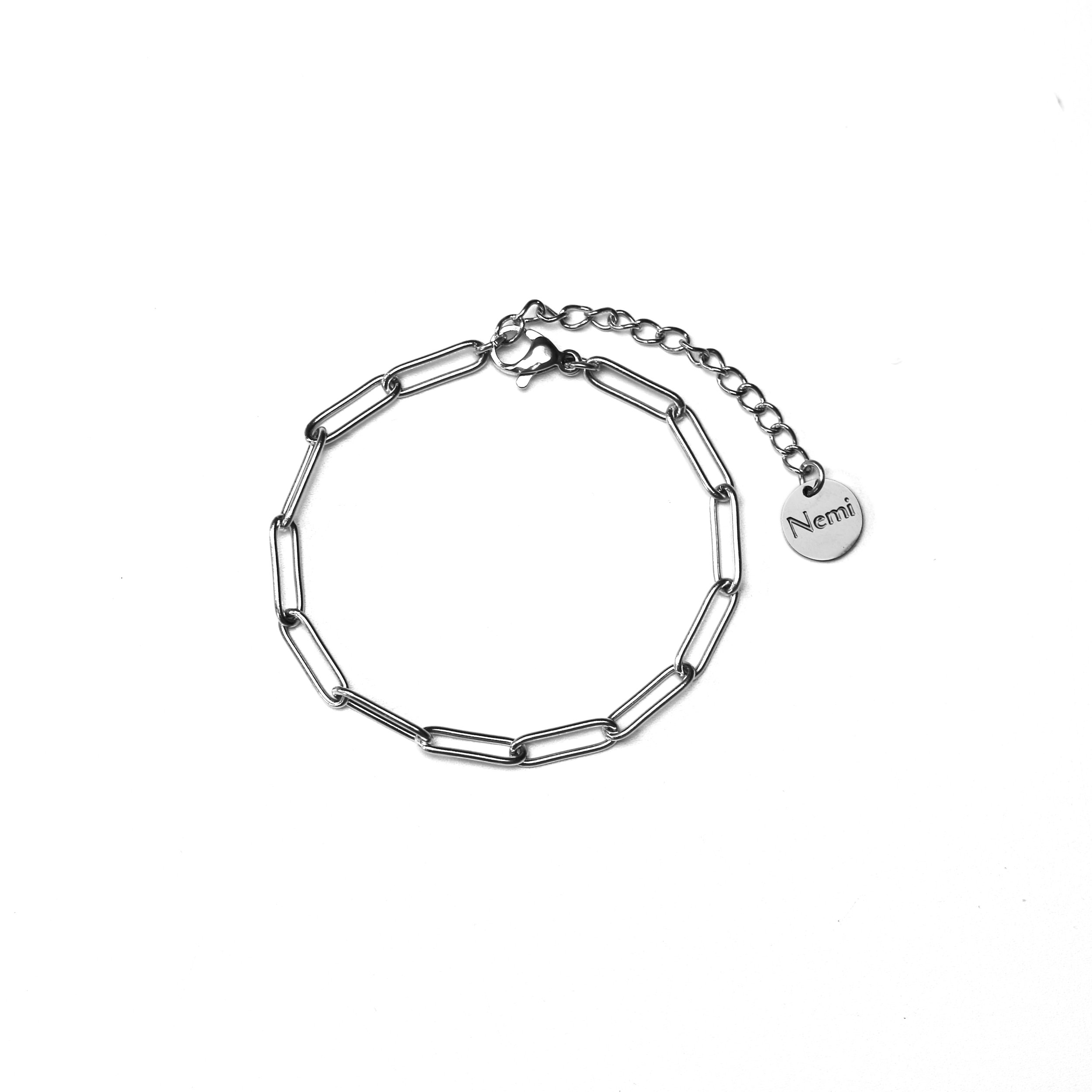 Silver chain bracelet with elongated links and a small round charm engraved with the name 'Nemi' on a white background.