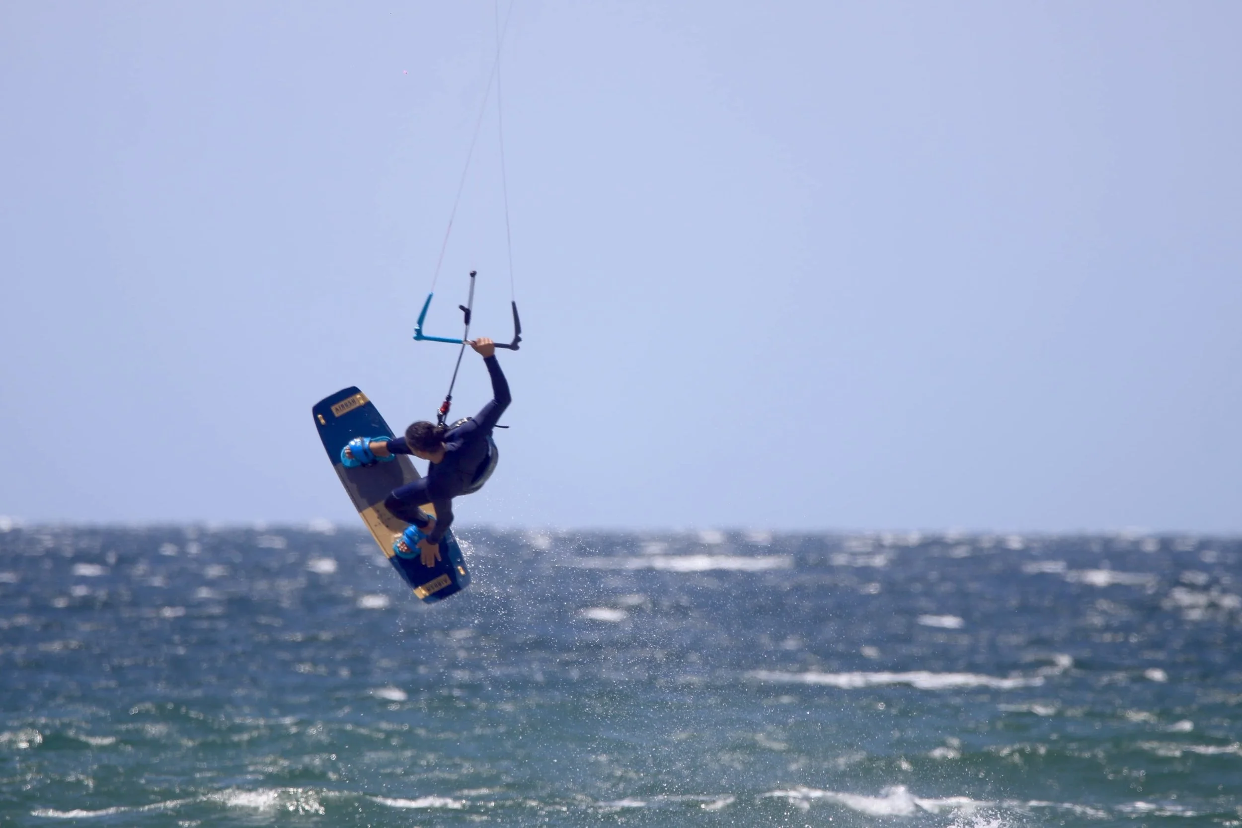 A person engaged in kite surfing over the ocean during the daytime.