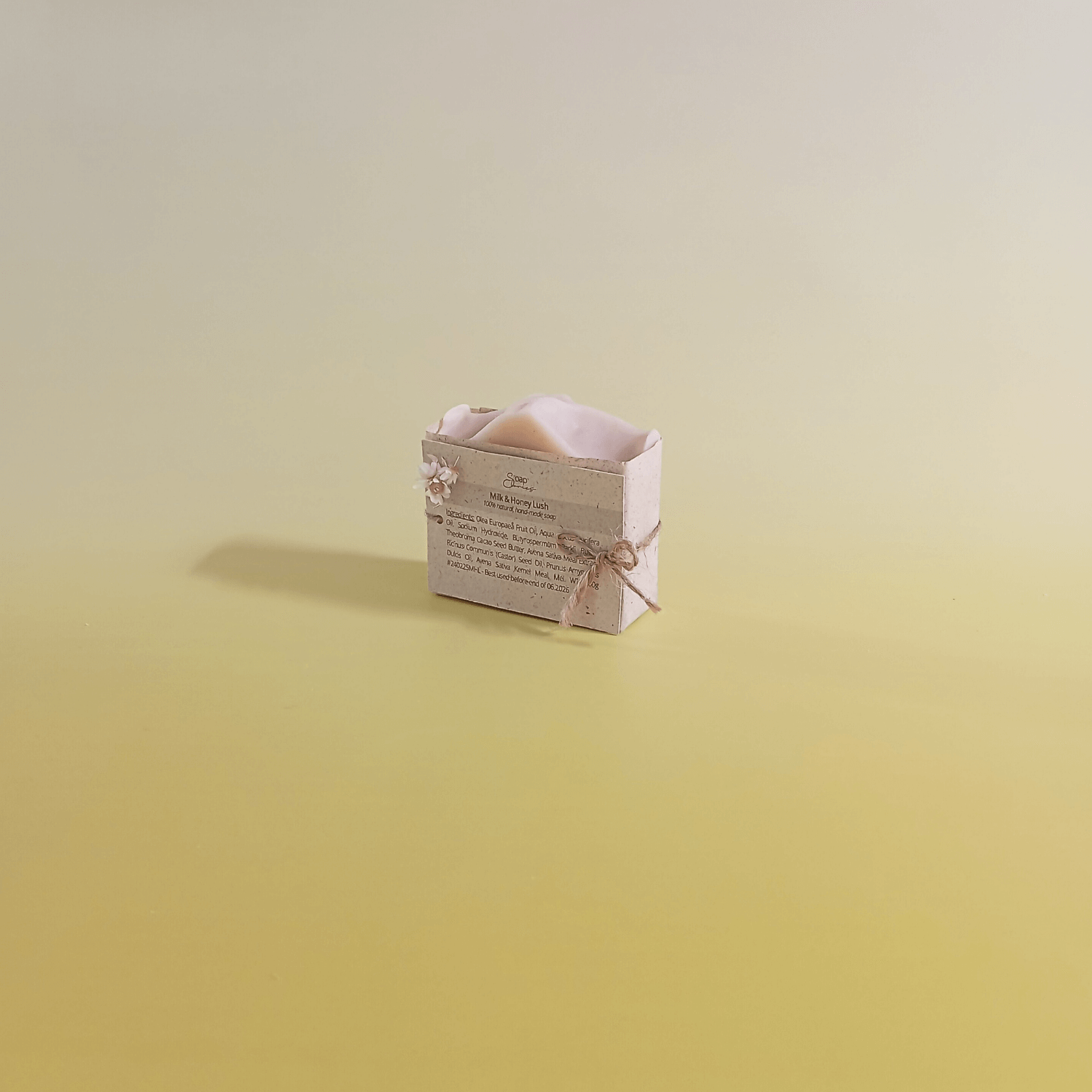Natural soap bar wrapped in eco-friendly paper and tied with natural twine, displayed on a soft yellow gradient background, reflecting minimal and sustainable design.