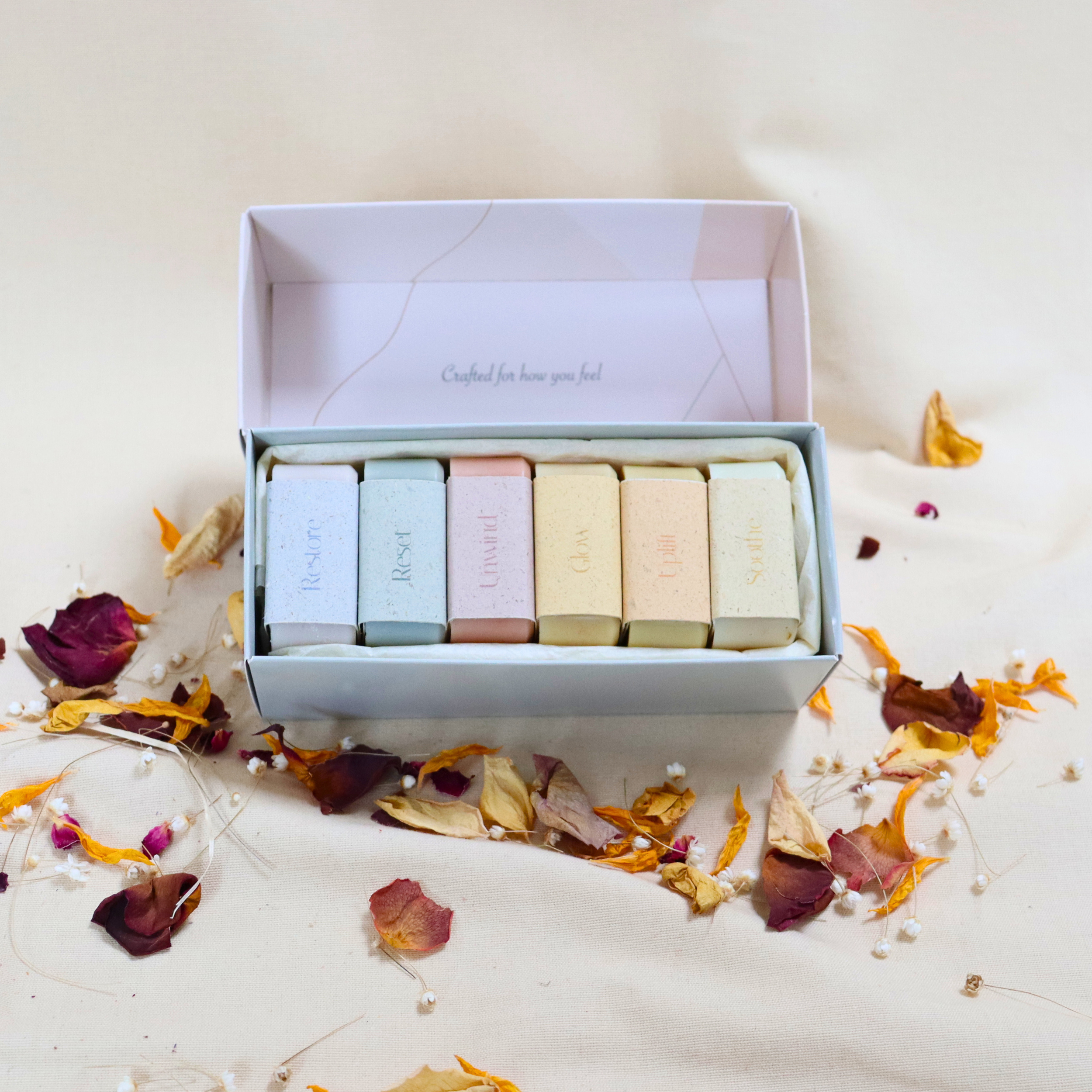 The Daily Edit box containing six handmade mini soaps by Soap Stories, surrounded by dried flower petals.
