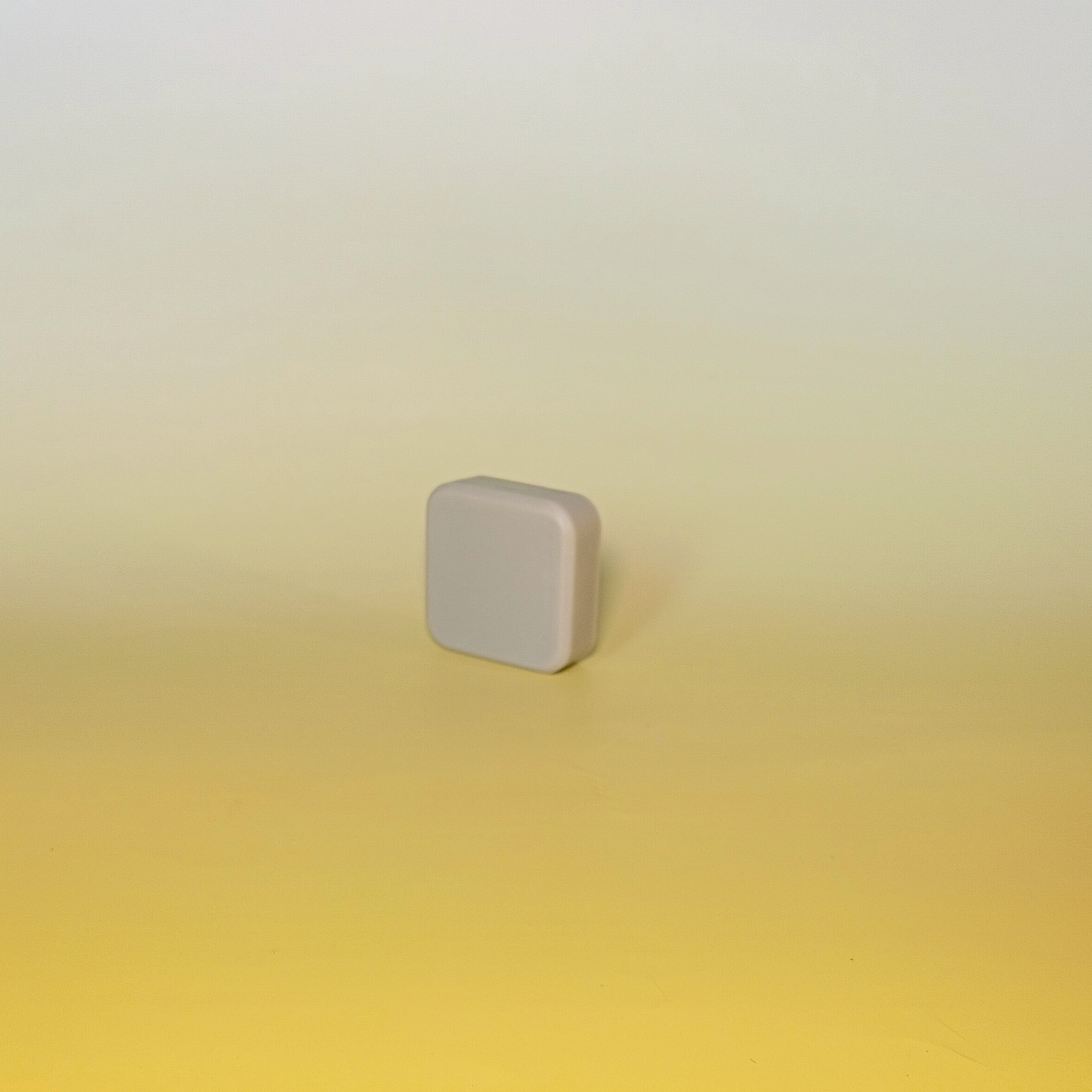 A single bar of handmade soap with soft green colour, displayed on a gradient yellow background.