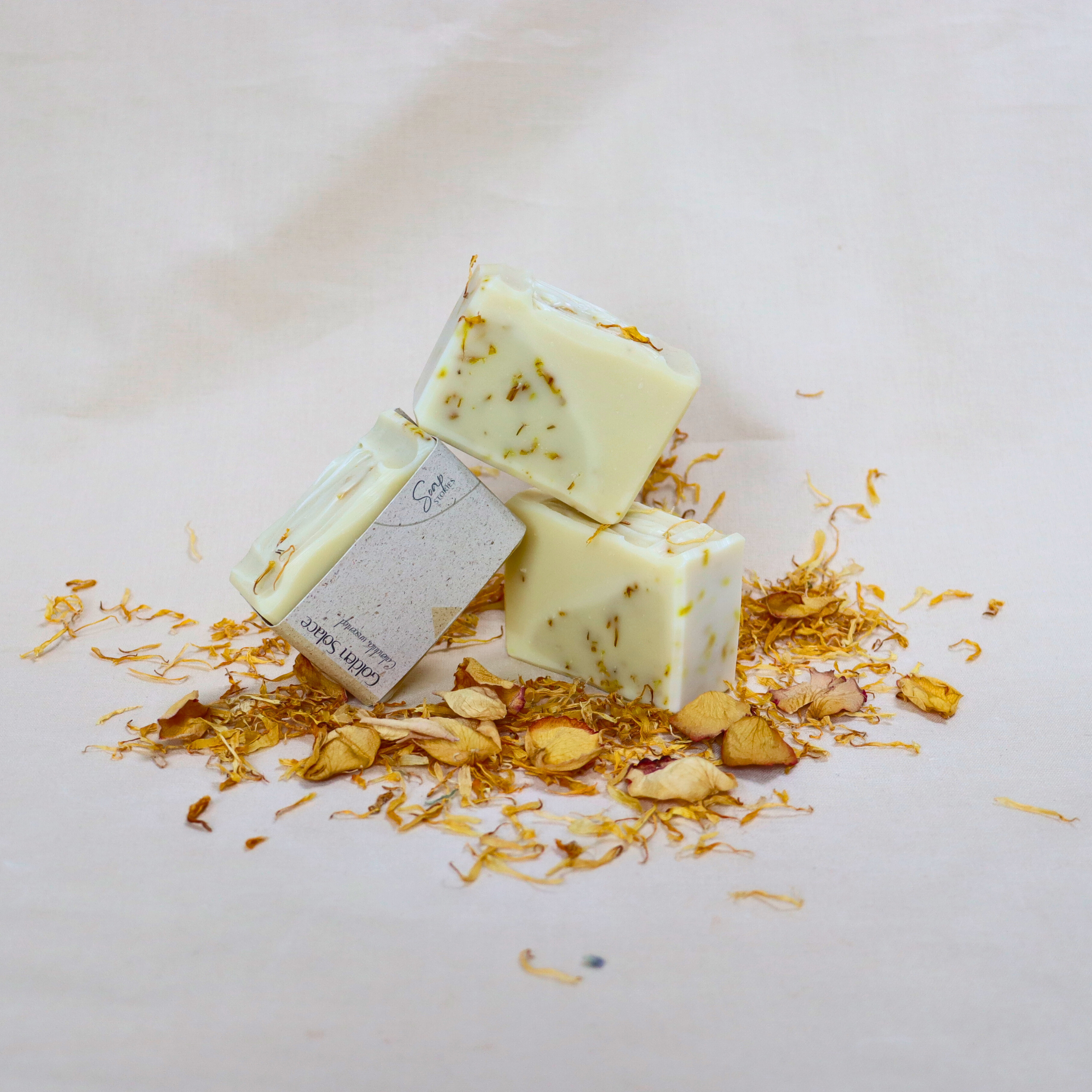 Handmade natural unscented calendula soap bar with dried calendula petals on a soft cream background, featuring a gentle yellow tone and a soothing minimalist look.