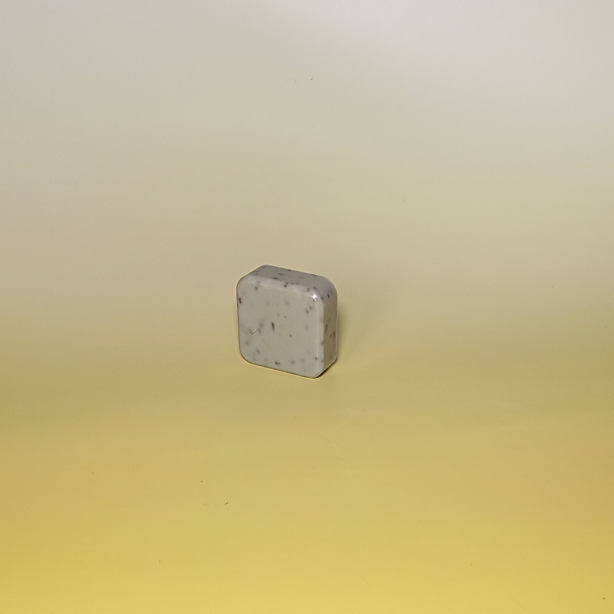 A single bar of handmade soap with soft green colour, displayed on a gradient yellow background.