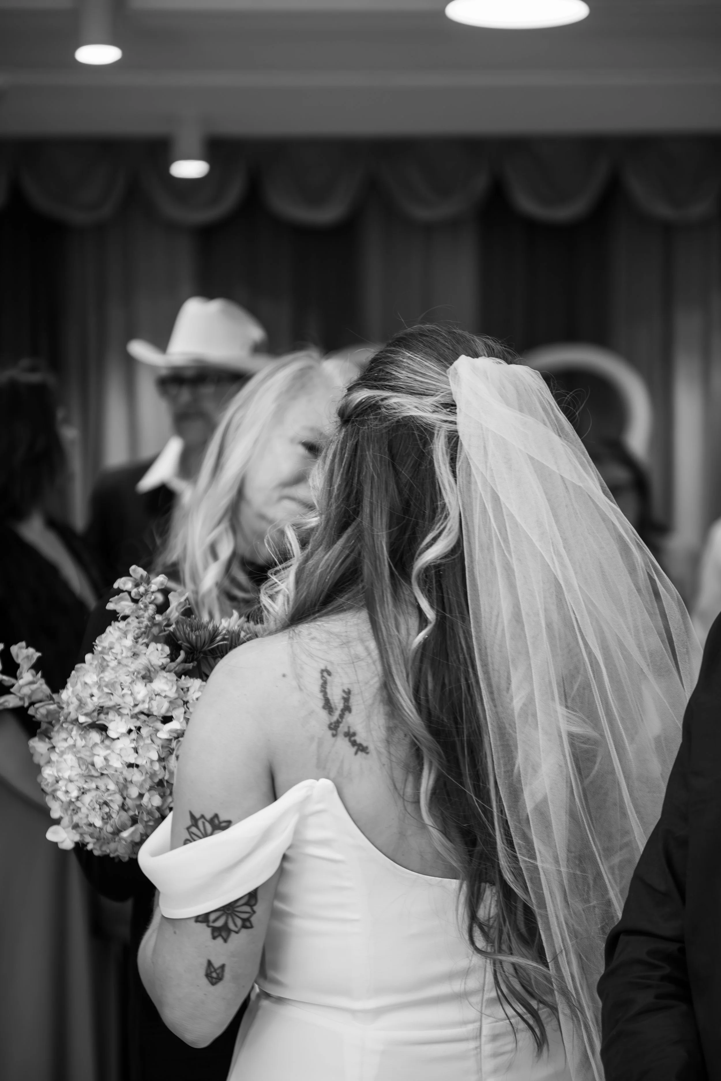 Bride with a veil and florals talking to her guests at Lucky In Love Chapel in a black and white photo 