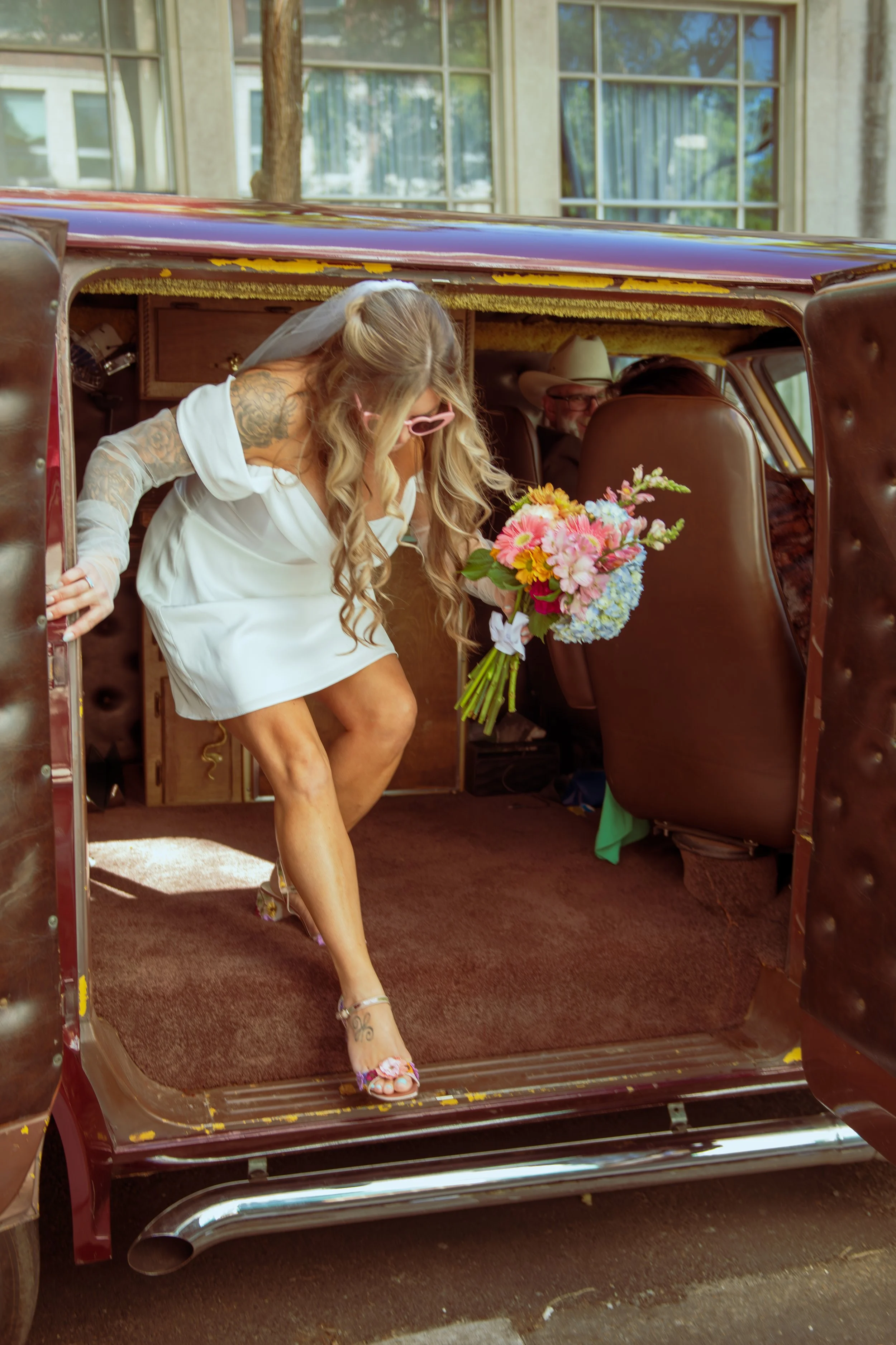 A bride getting out of a retro van to her wedding day