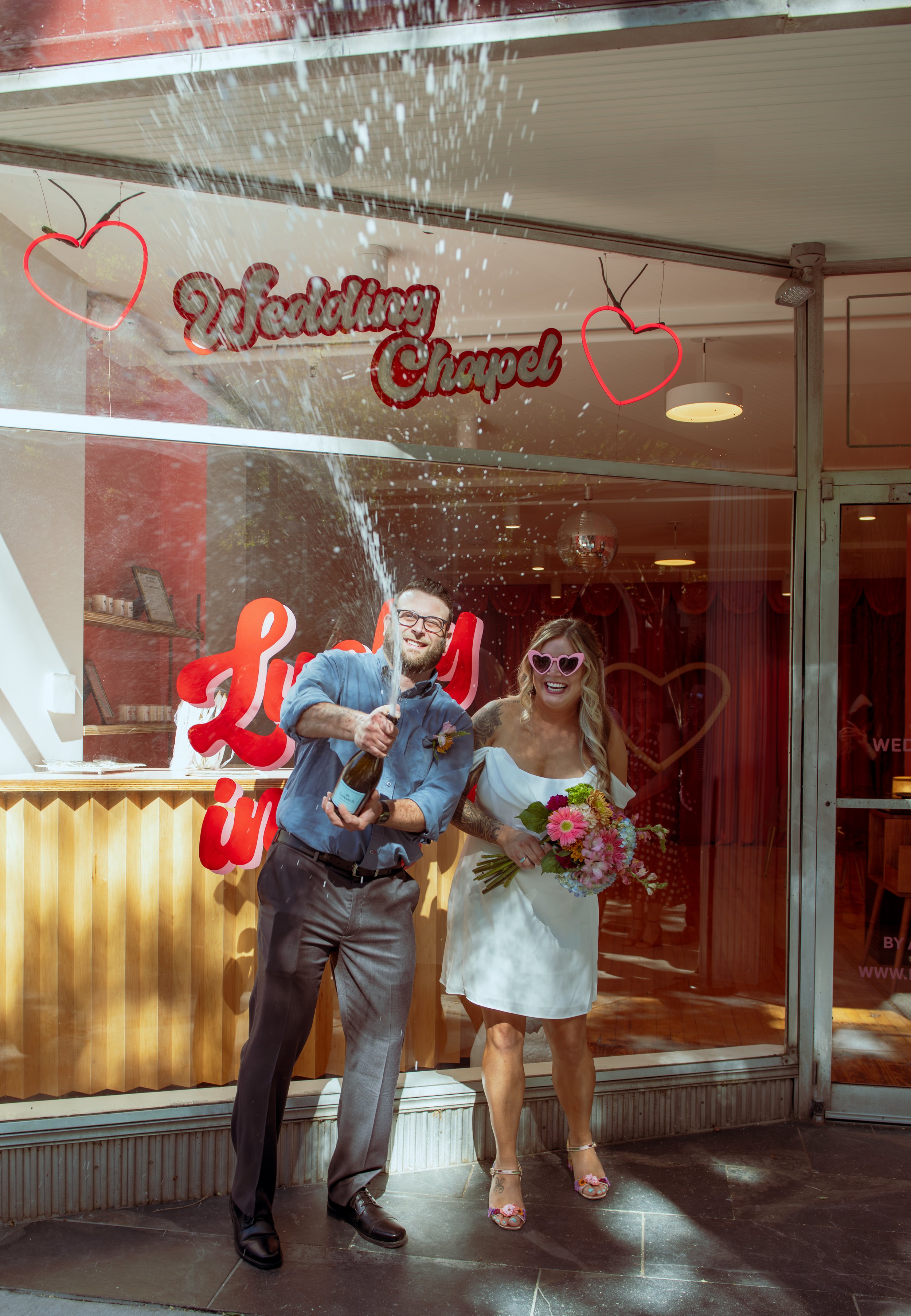 A couple popping the bottle outside of the chapel after getting married at the heart altar