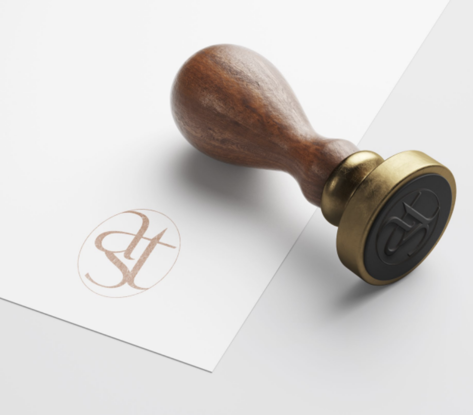 Un tampon en caoutchouc avec un manche en bois, posé sur une feuille de papier blanc avec un logo imprimé.