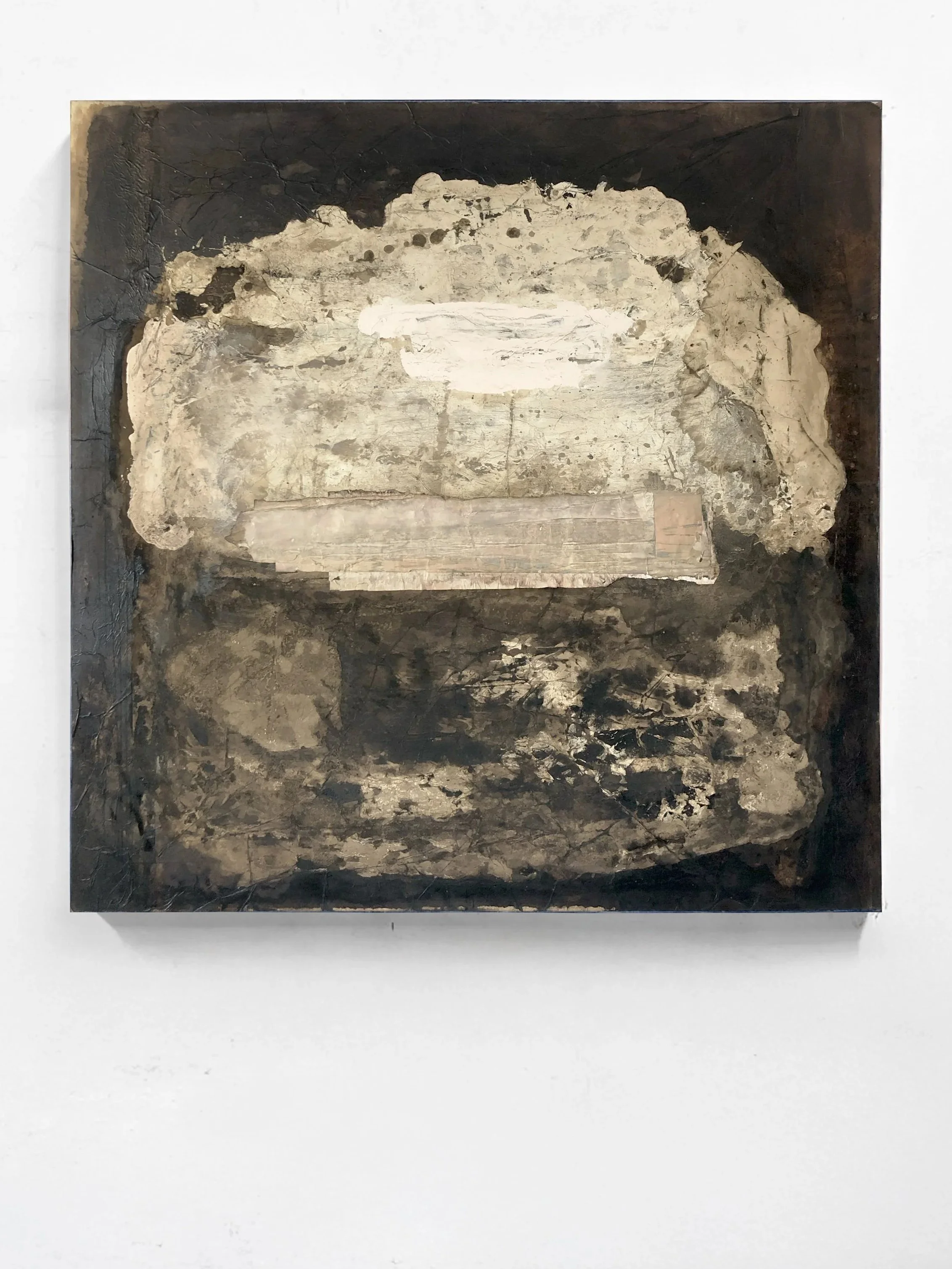 Abstract mixed media artwork featuring layered textures in neutral tones, mounted on a white wall.