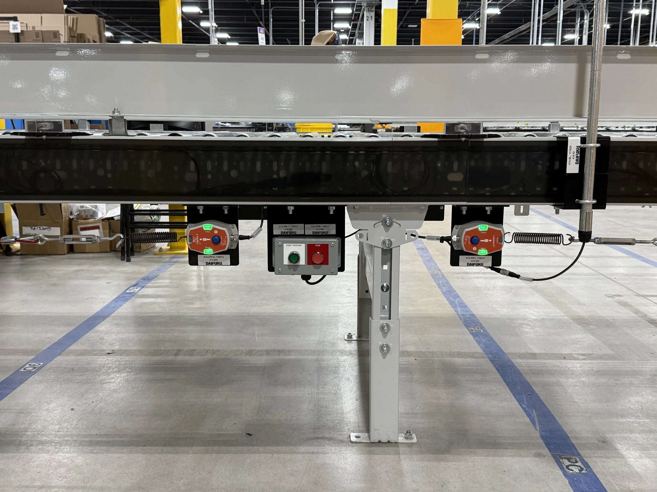 An industrial conveyor belt system with control panels and buttons in a warehouse setting.