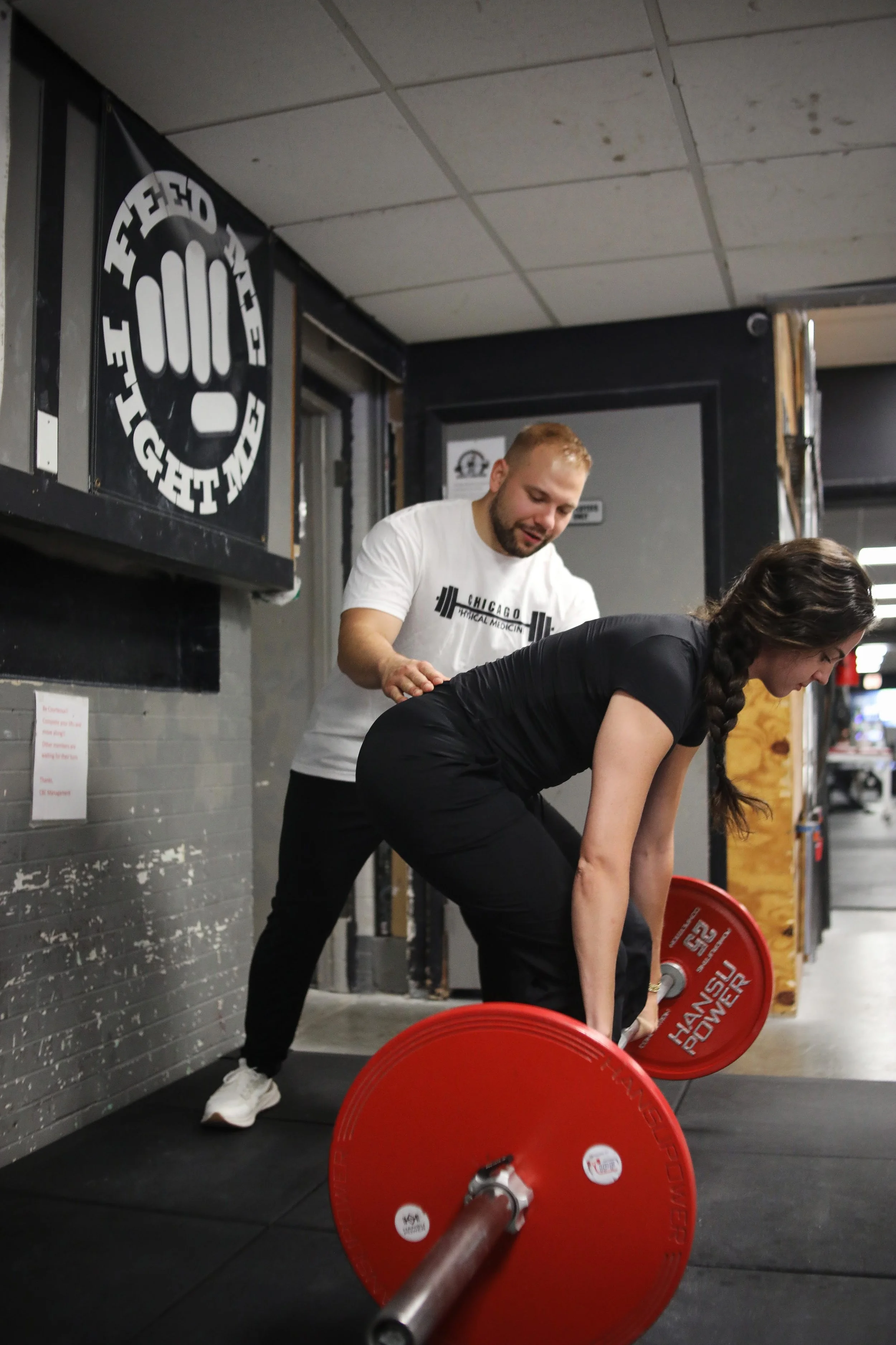 Dr. Krystian Garbicz coaching a woman through a barbell deadlift