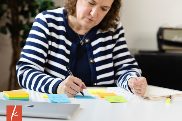Kathleen Lawson at her desk writing on post it notes