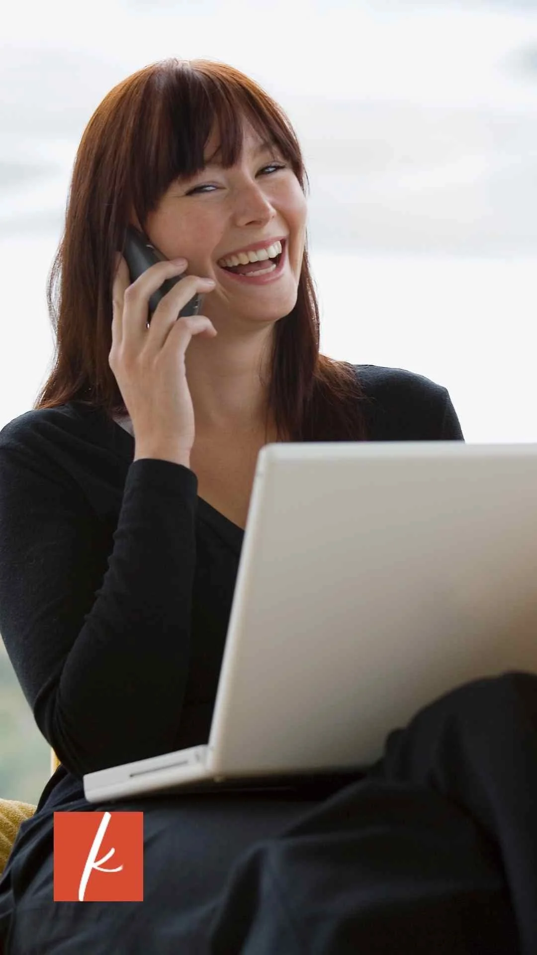 Woman on a phone call laughing with a computer at her desk