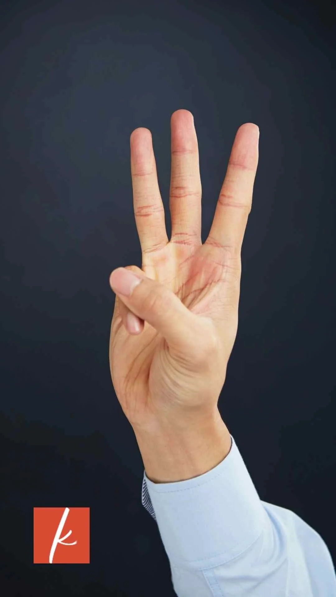 Hand holding up three fingers against a dark background.