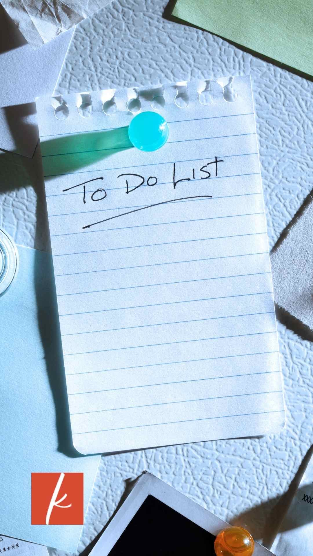 Handwritten to-do list on lined paper pinned to a wall with a blue pushpin