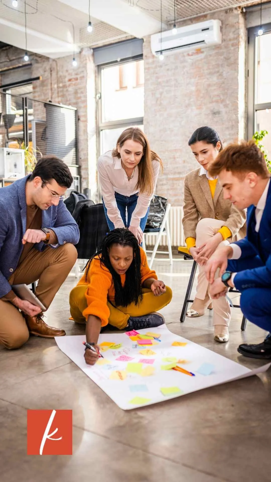 A group of women and men sitting around a poster with sticky notes planning.