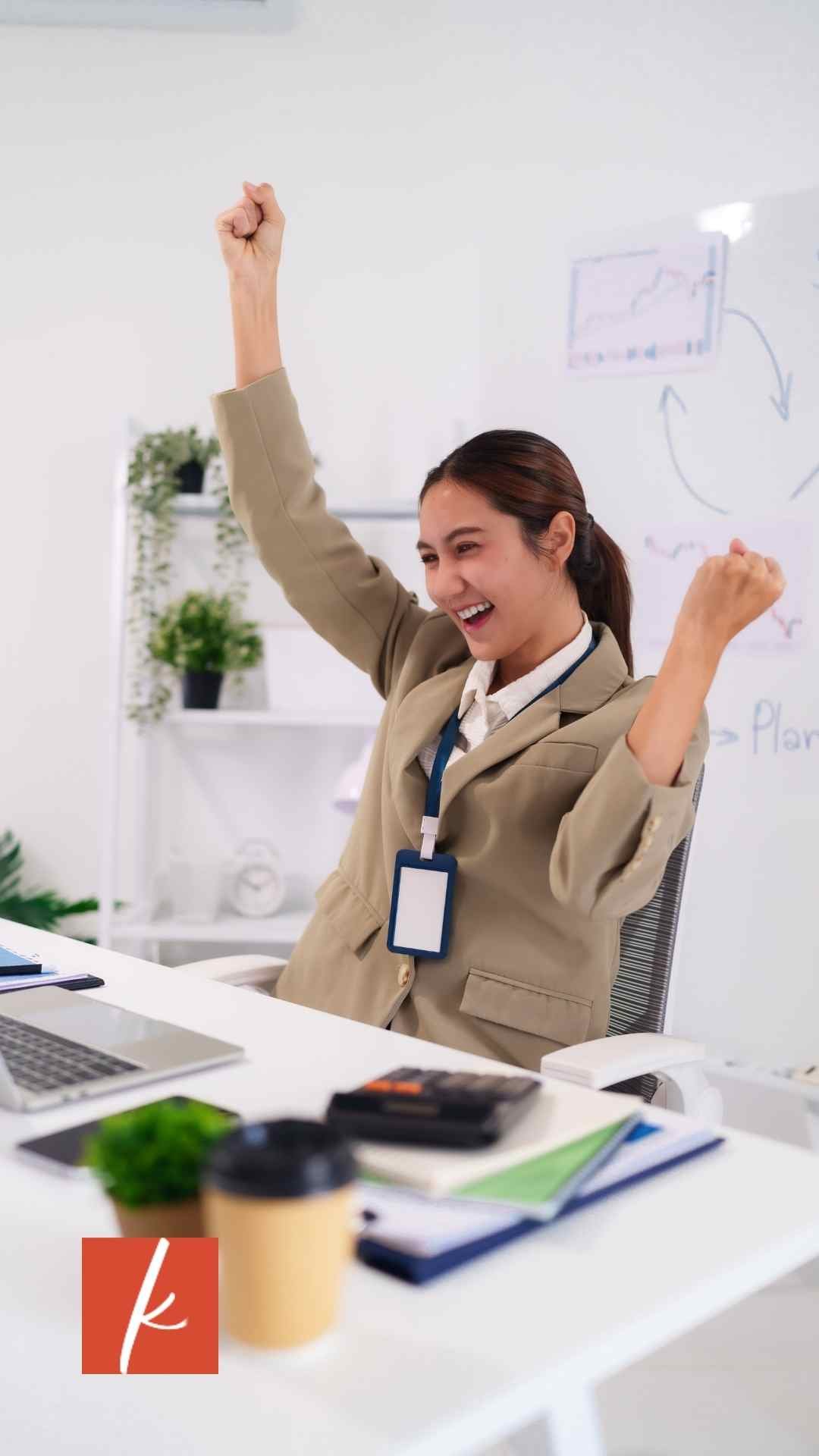 Woman business owner sitting at desk with her computer celebrating after finishing her CEO Hour