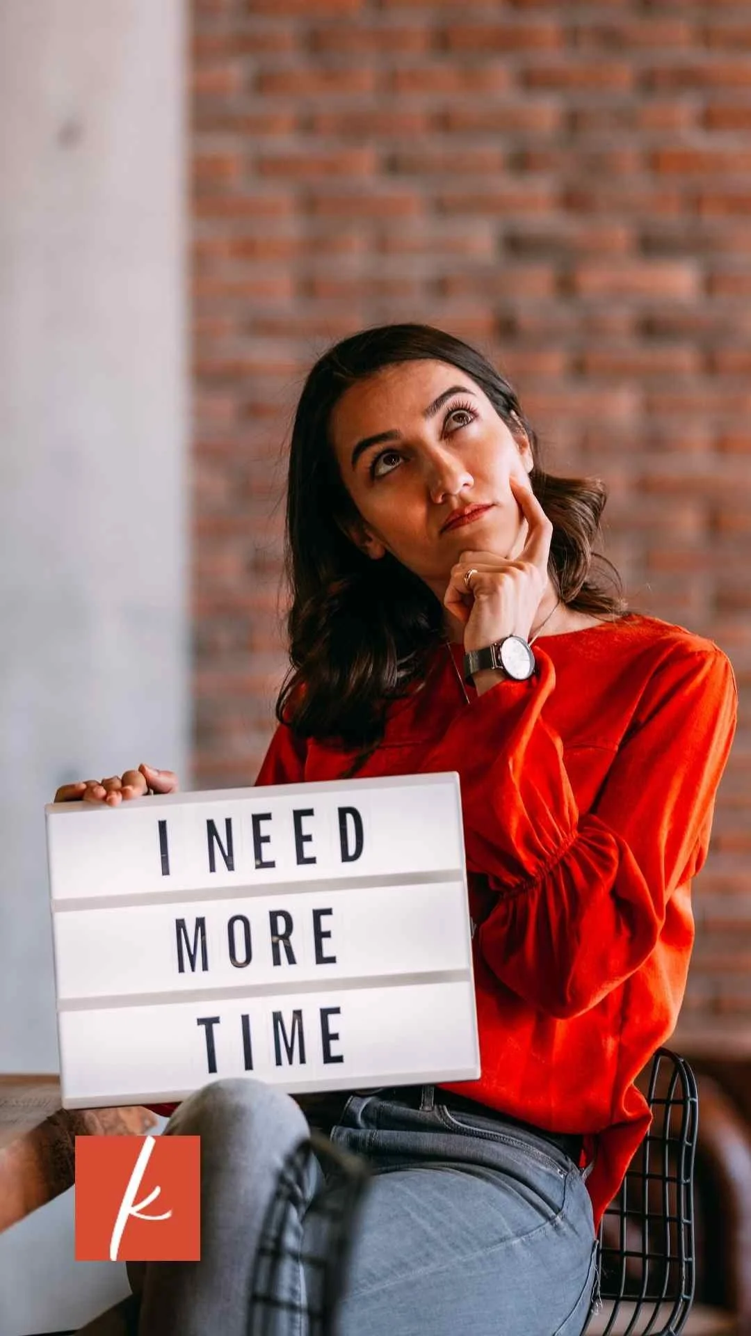 Woman holding a sign that reads ‘I need more time’ while looking thoughtful.