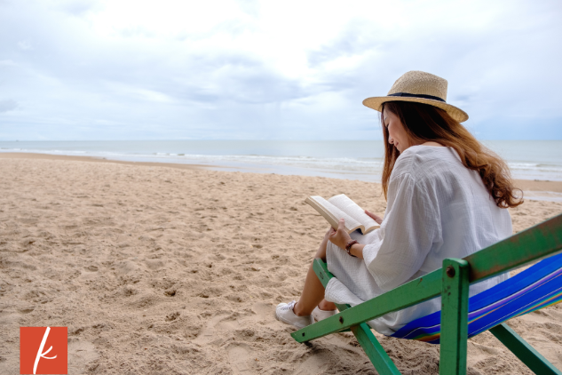 Woman on the beach sitting on a chair reading a book