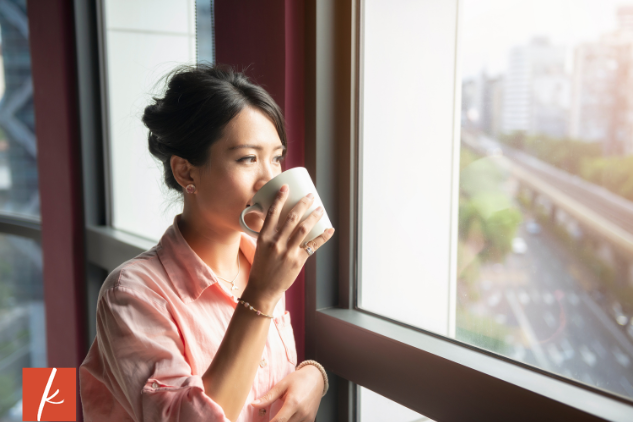 Women drinking a coffee looking out the window.