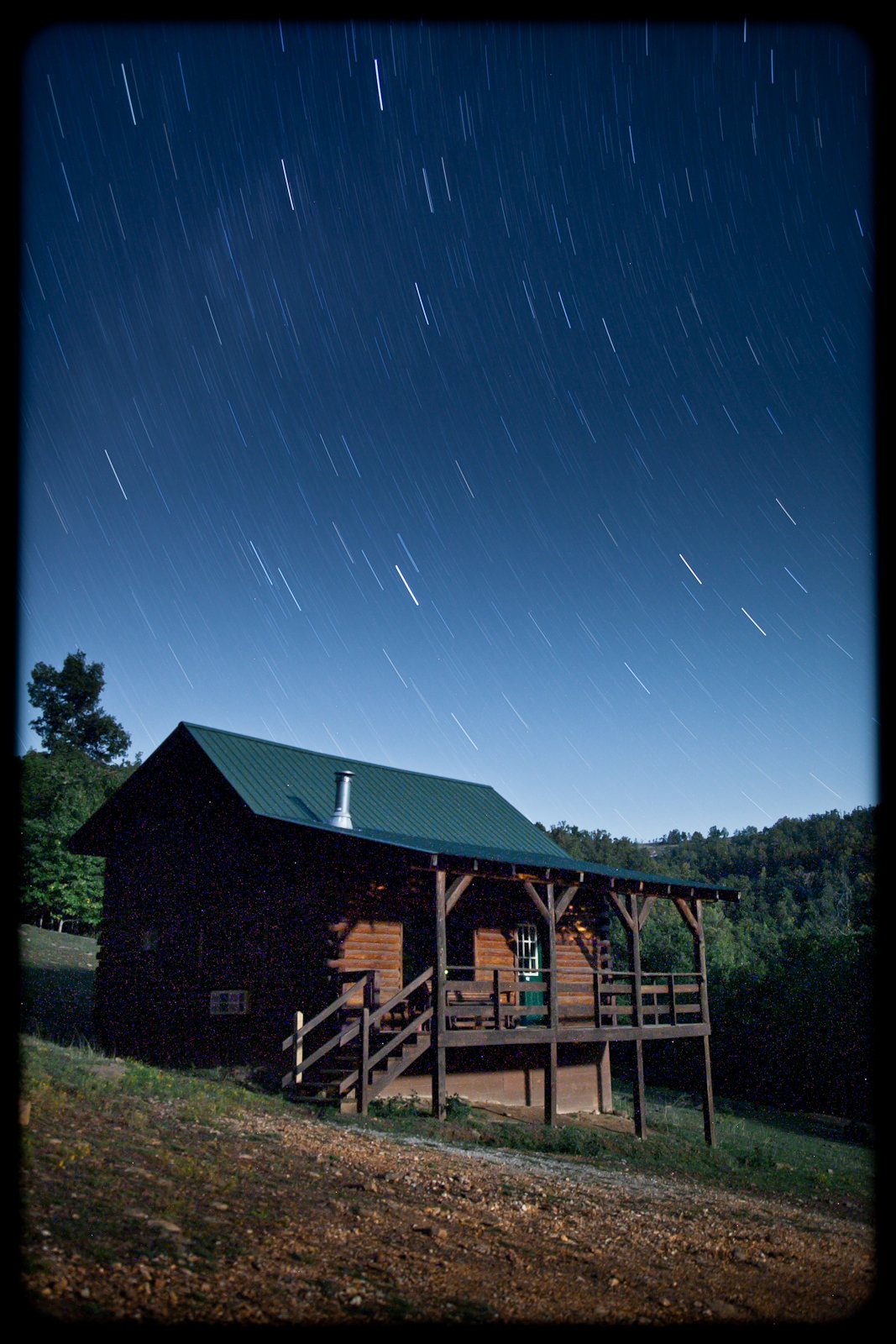 Nighttime scene of a wooden cabin with a metal roof under a starry sky.