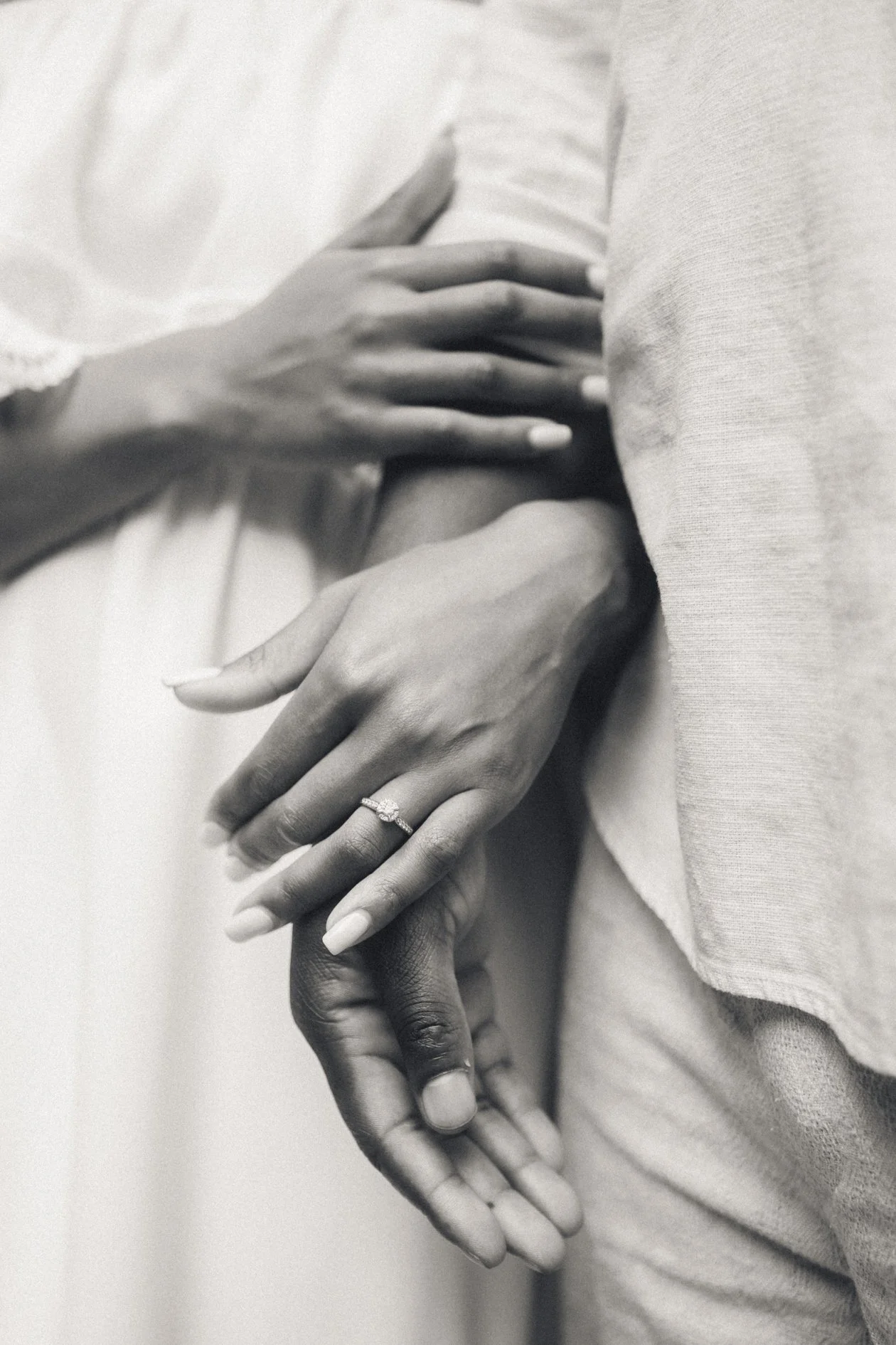 Close-up of two hands, one with a ring on the ring finger, gently holding each other.