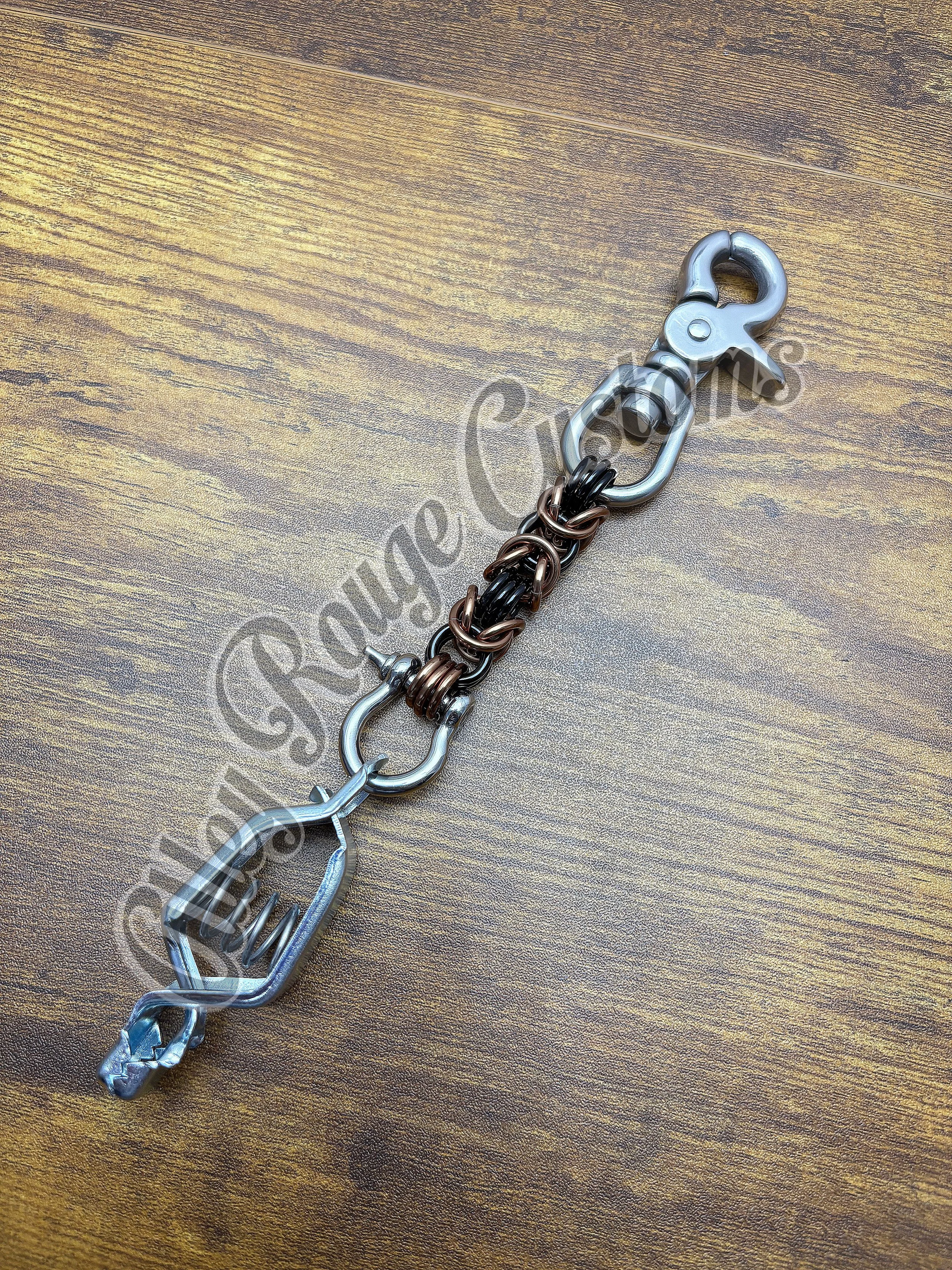A keychain made of metal chains and clips, with a clasp at one end, lying on a wooden surface.