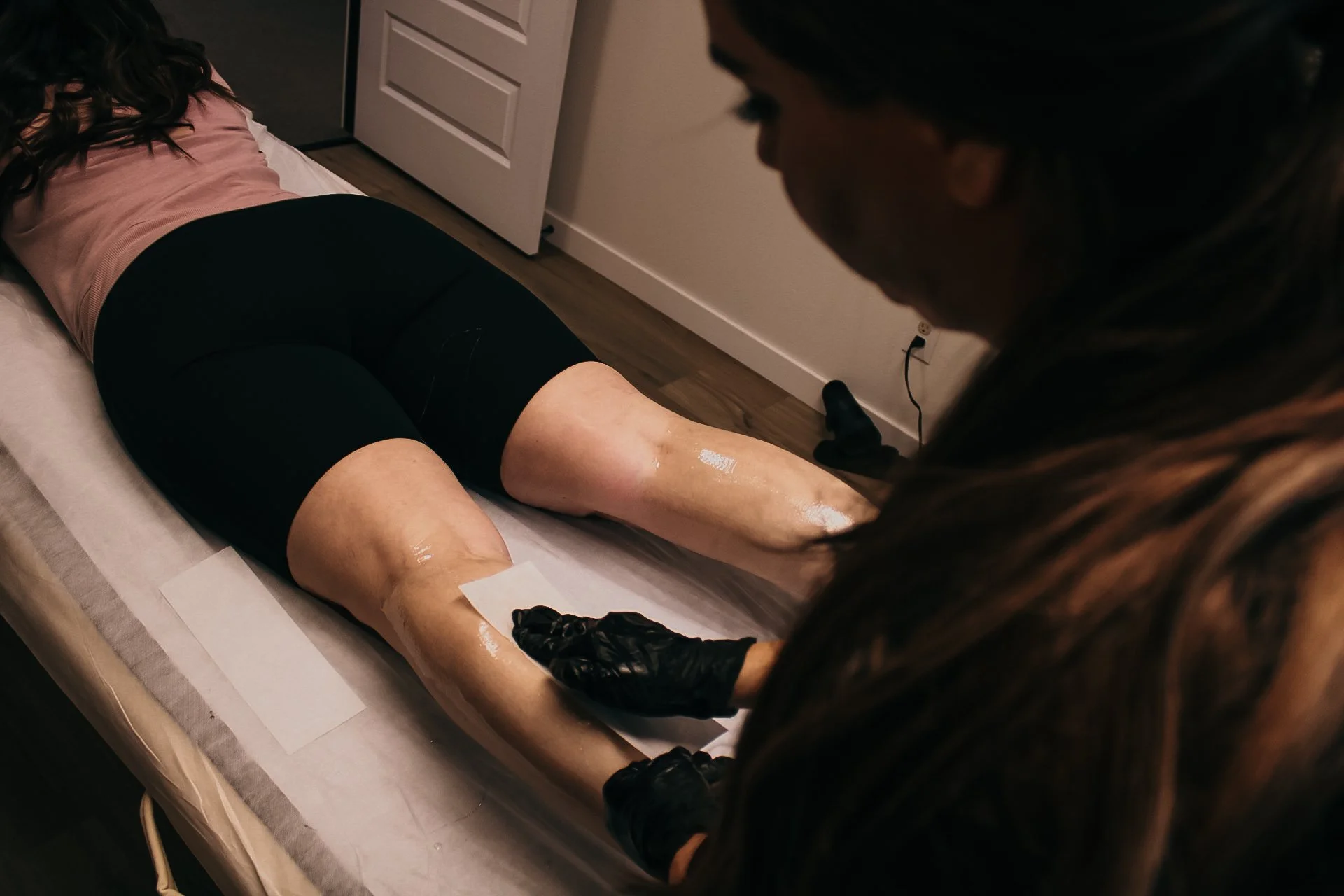 An esthetician waxing the back of a client's legs