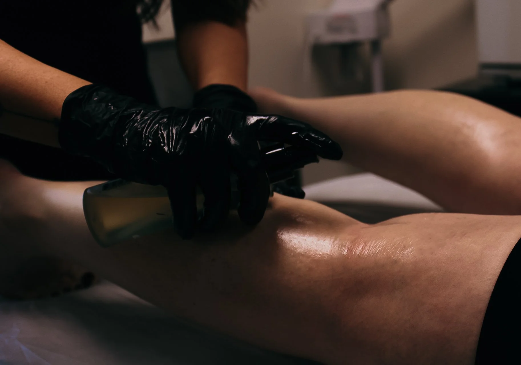 Esthetician applying an aftercare product to a client's legs post waxing