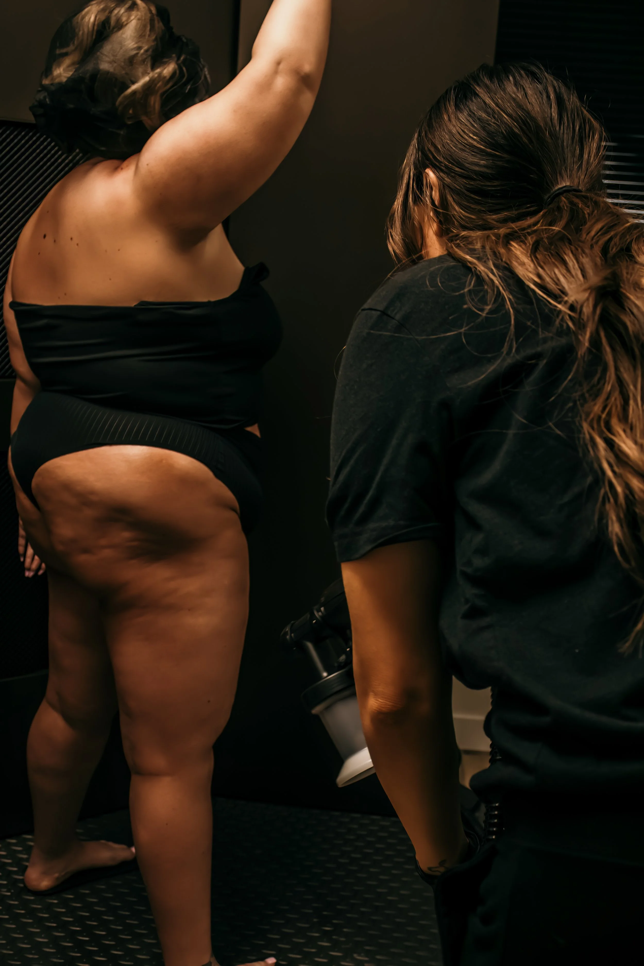 A woman receiving a spray tan on her legs
