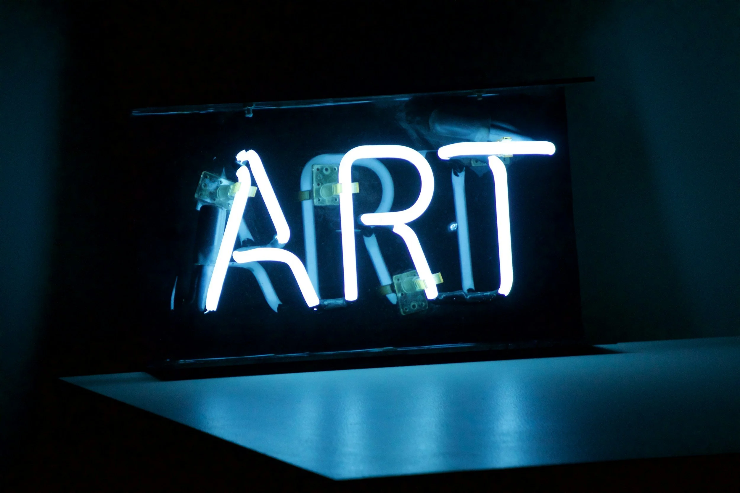Neon sign displaying the word 'ART' in a dark setting.