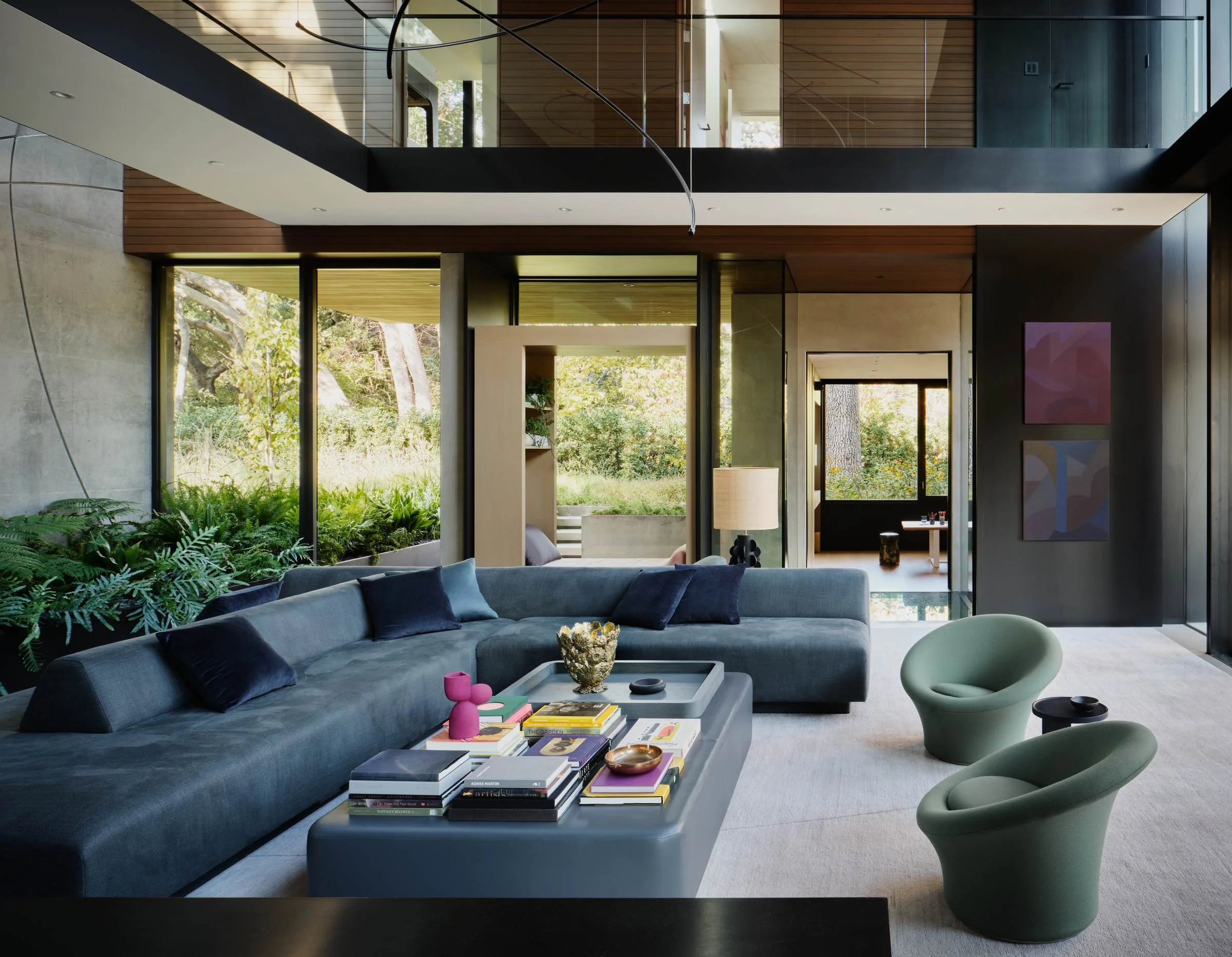 Floor-to-ceiling glass doors open a living room to the wooded landscape beyond.