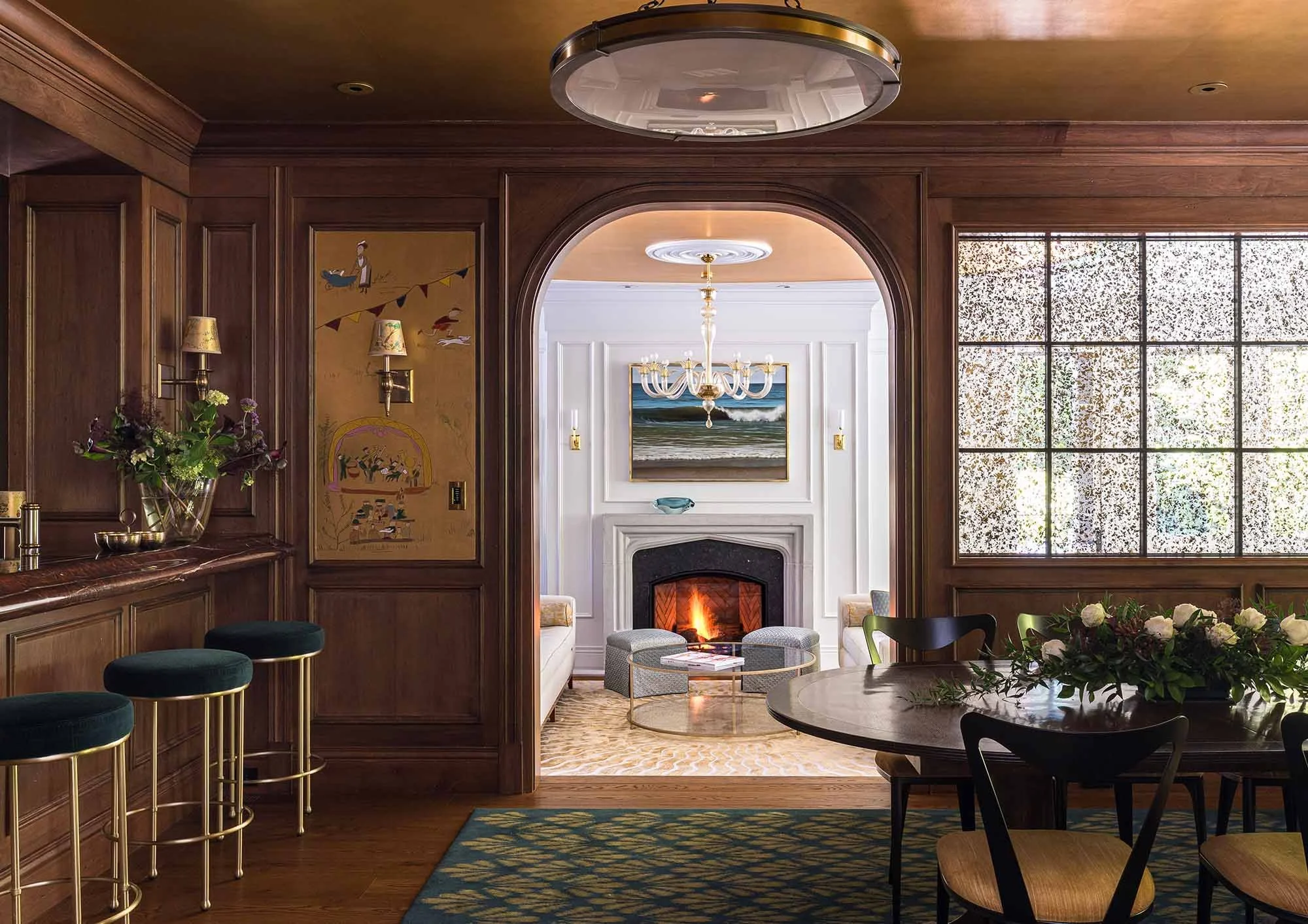Custom arched wood passageway connecting a paneled bar room to a formal living room, crafted by West Coast Architectural