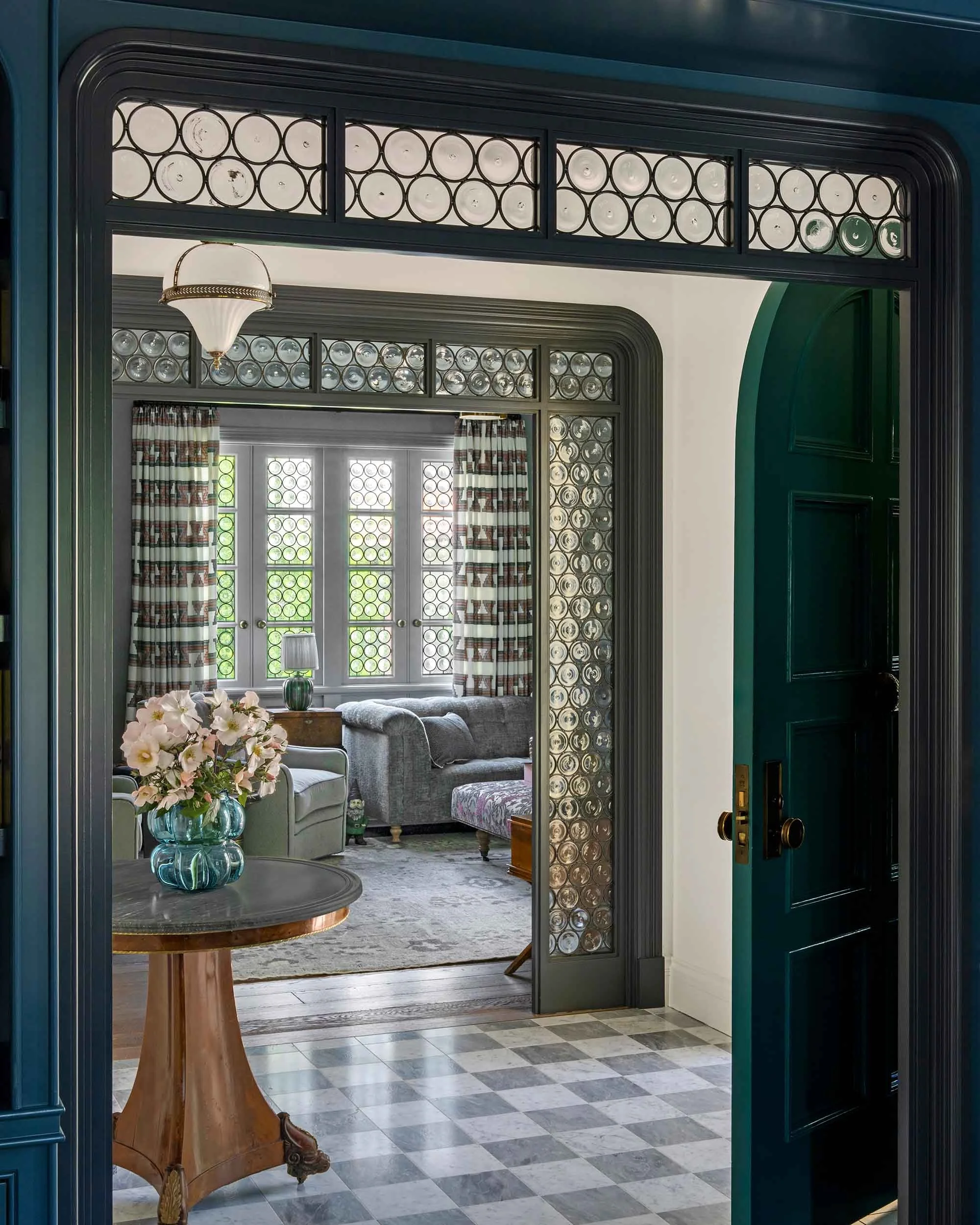 Custom bull's-eye leaded glass transom and sidelights framing arched passage into living room.