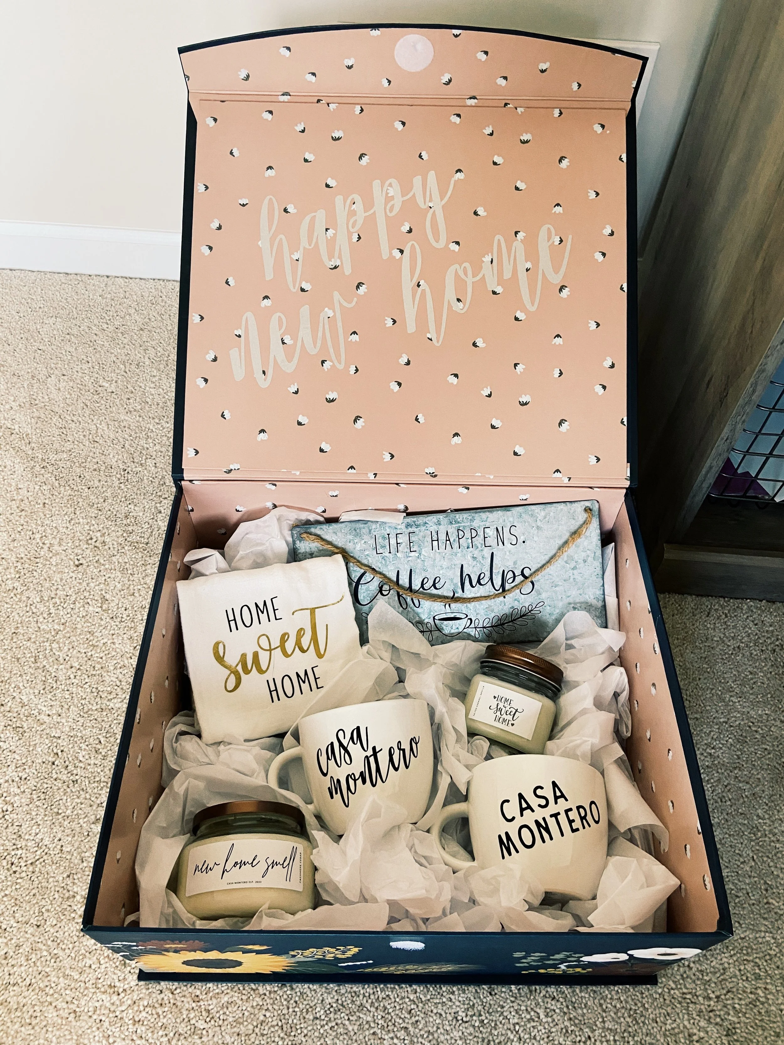 custom housewarming gift box with mugs, various candles, a tea towel, and a sign