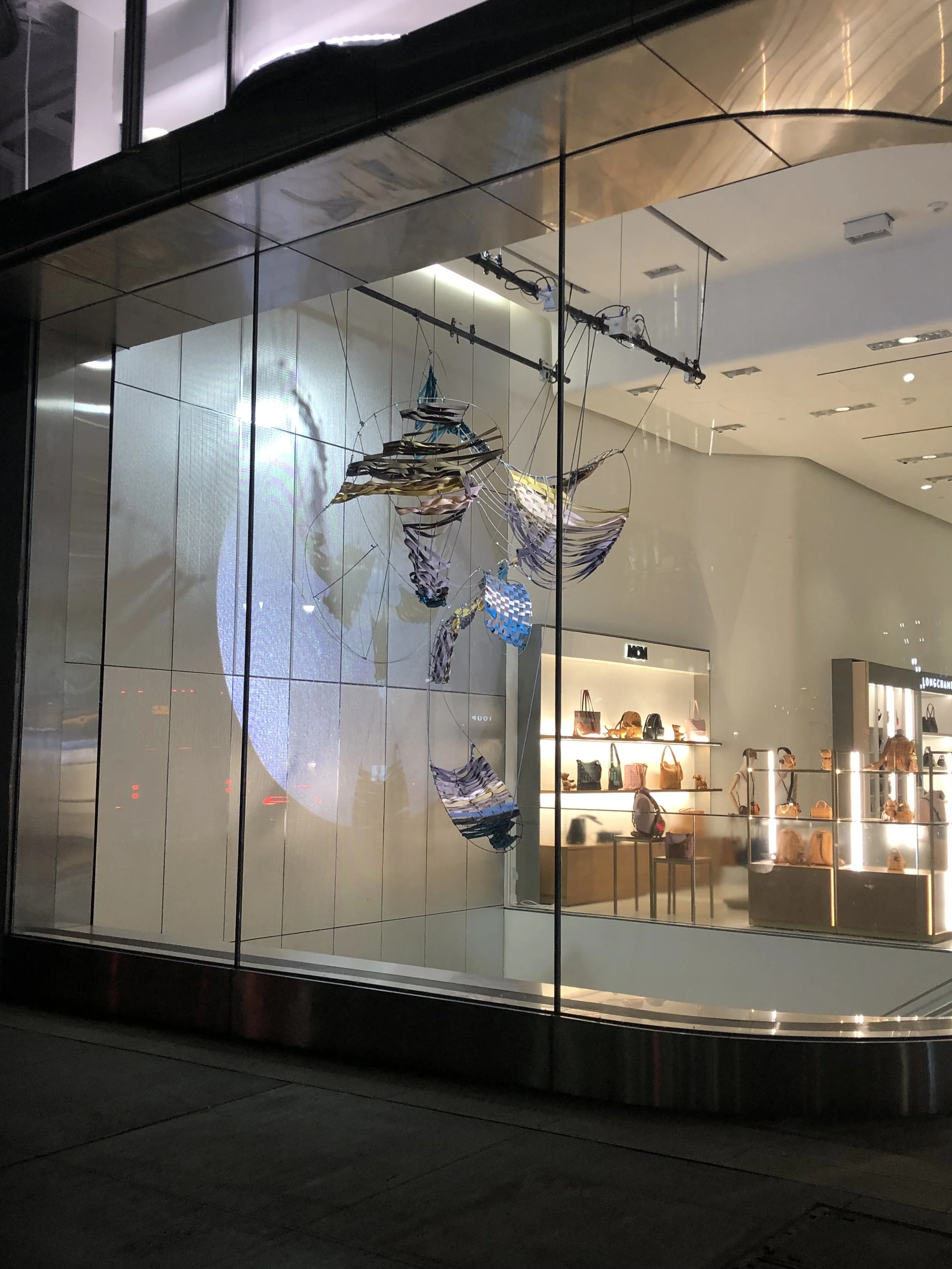 Nordstrom front window display with gallery setup against back light wall taken at night
