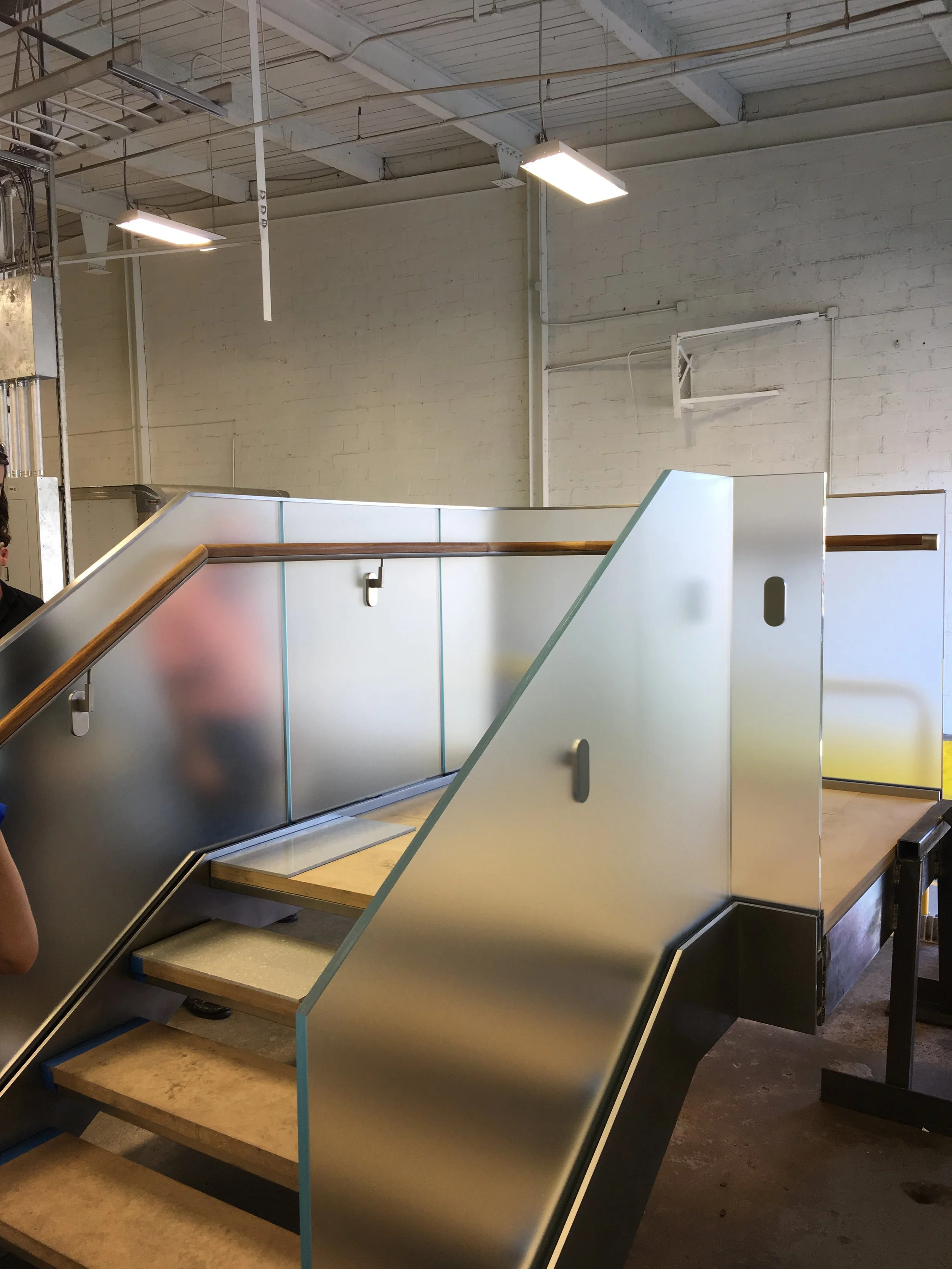 Prototype stair mockup with diffused glass and wooden handrail at Amuneal fabricators