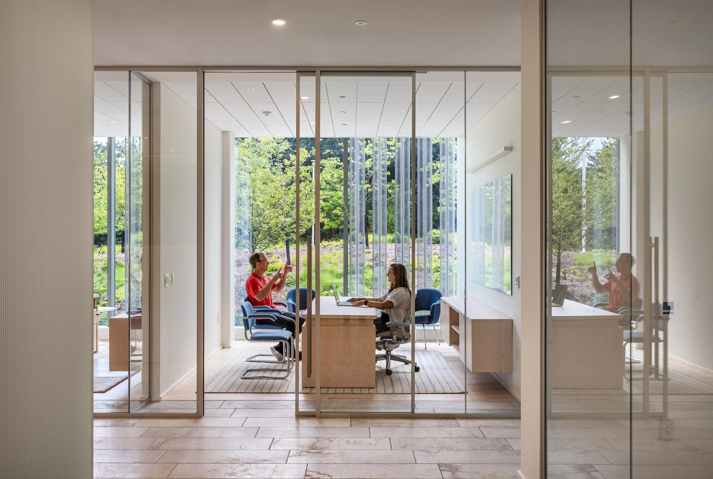 Office space in use showing floor to ceiling windows with view to nature outside