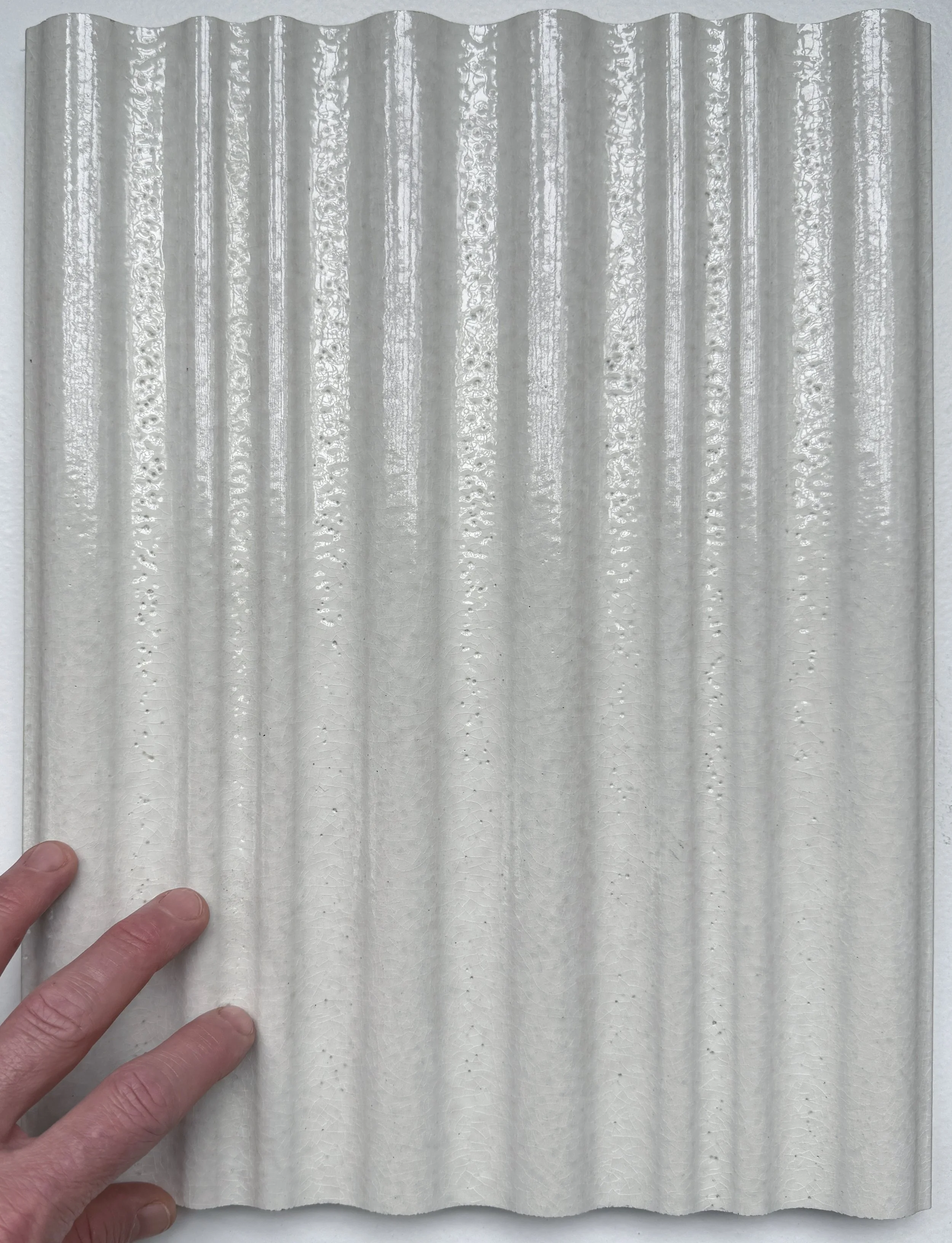 Extruded terracotta plank by Moeding with the same geometric wave design and a crackle glaze used for elevator walls